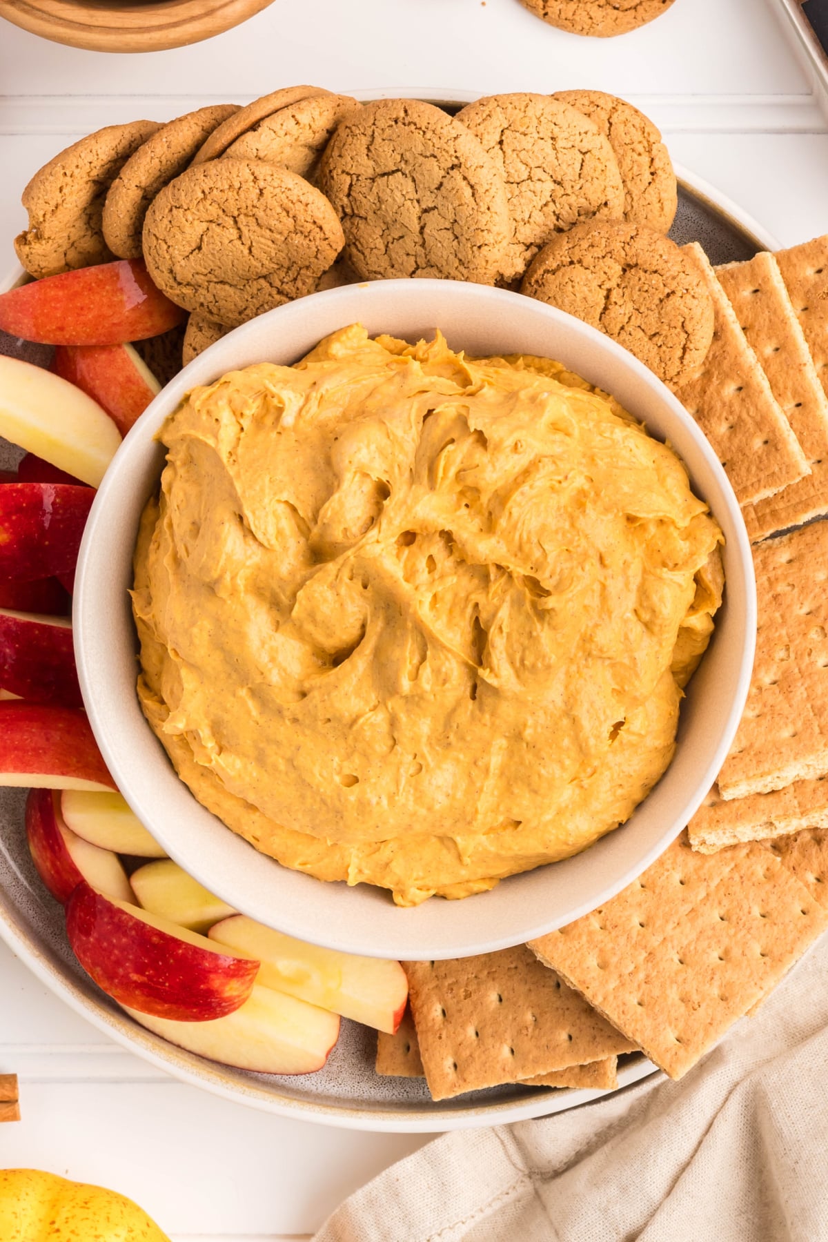 The fluff in a bowl surrounded by crackers and apples.