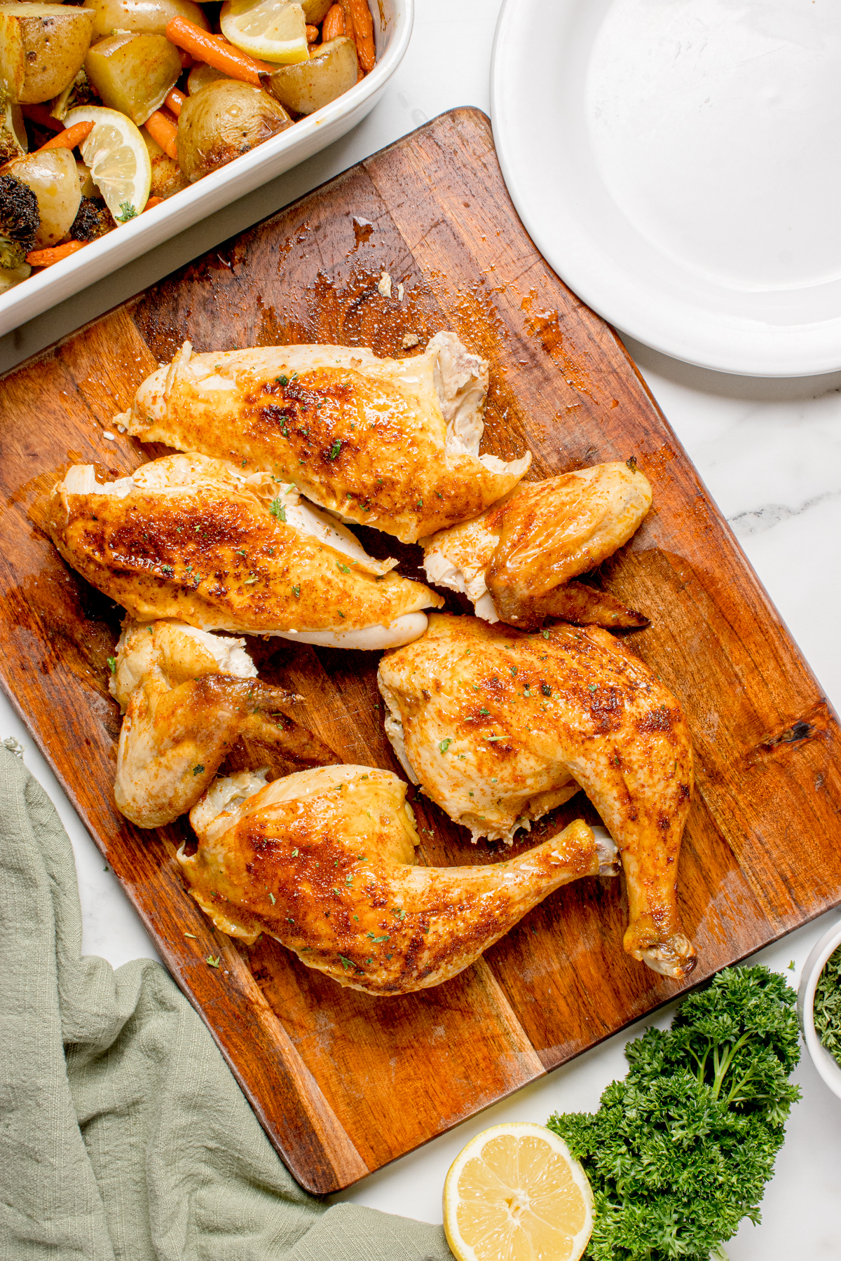 The chicken cut up into pieces on a cutting board.