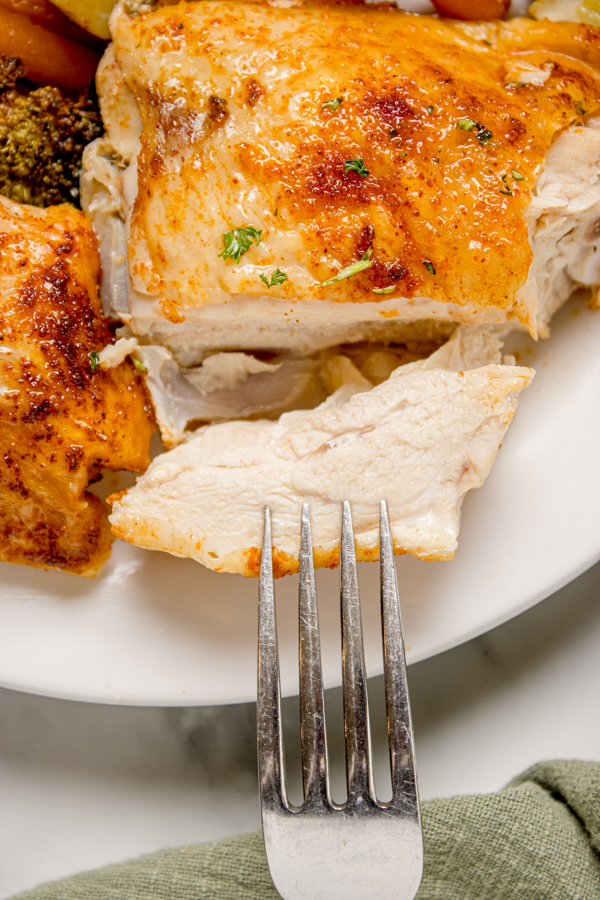 A fork getting ready to take a piece of spatchcock chicken.