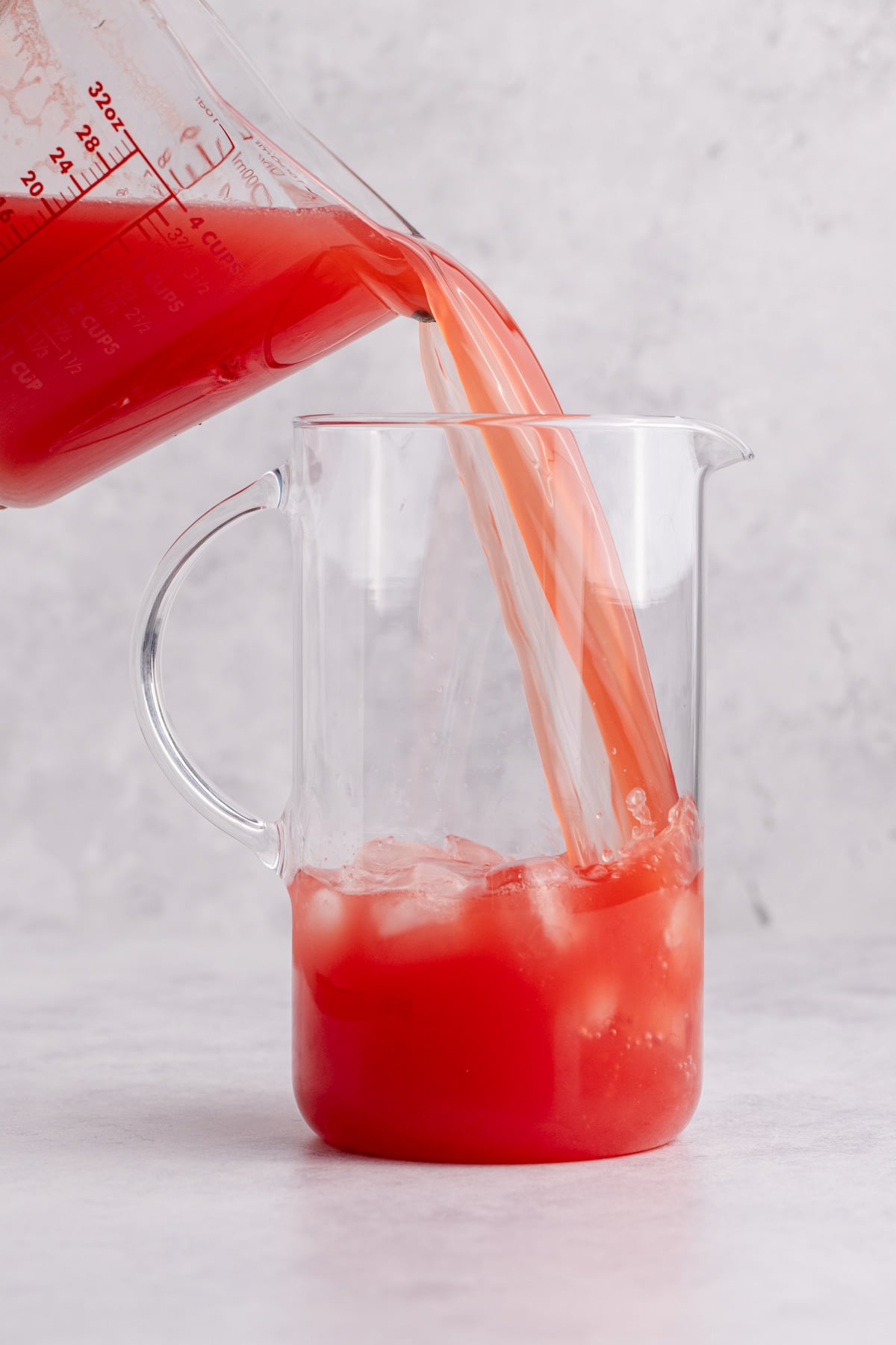 The drink being poured it into a pitcher with ice.