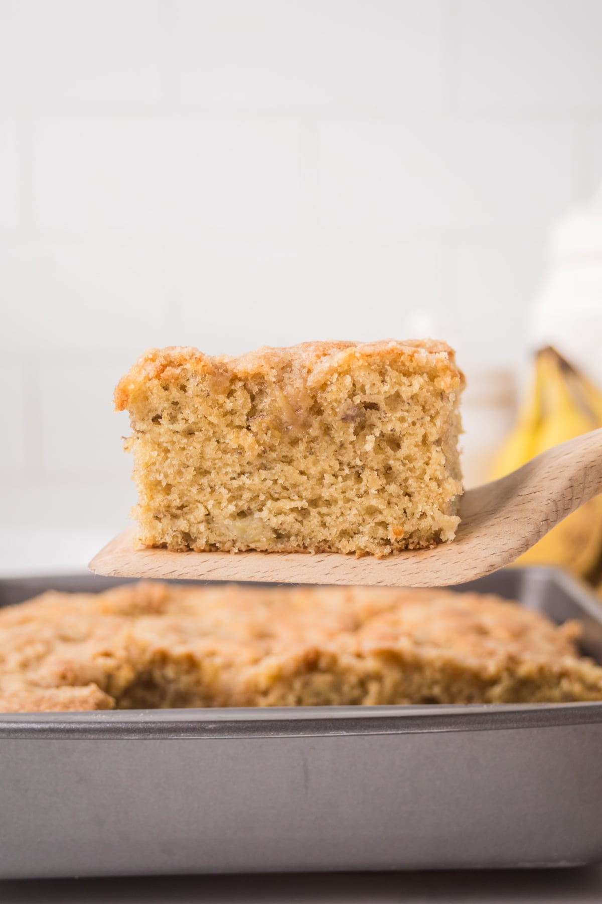 banana coffee cake slice held in air on wooden spatula