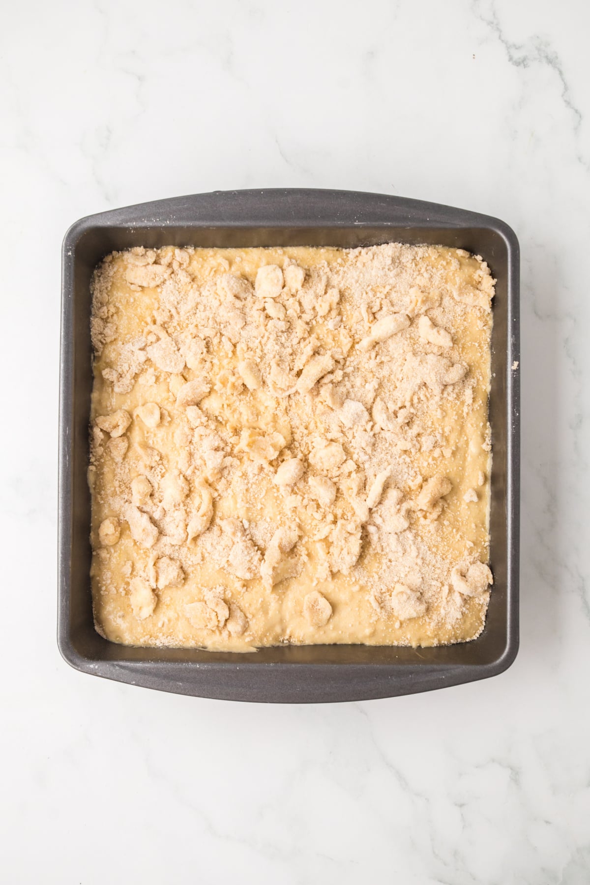 banana coffee cake batter spread in baking dish withcrumb topping 