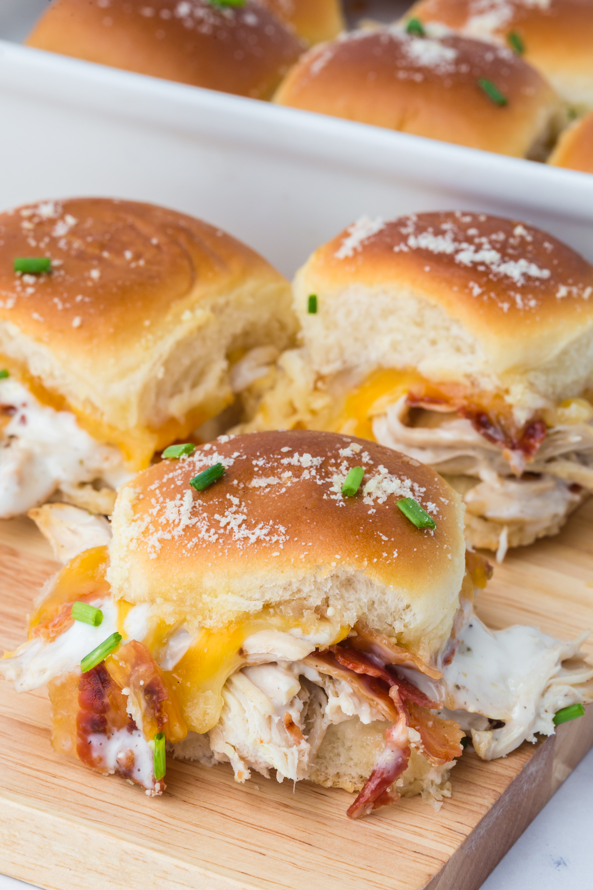 A chicken bacon ranch slider on a cutting board with more in the background.