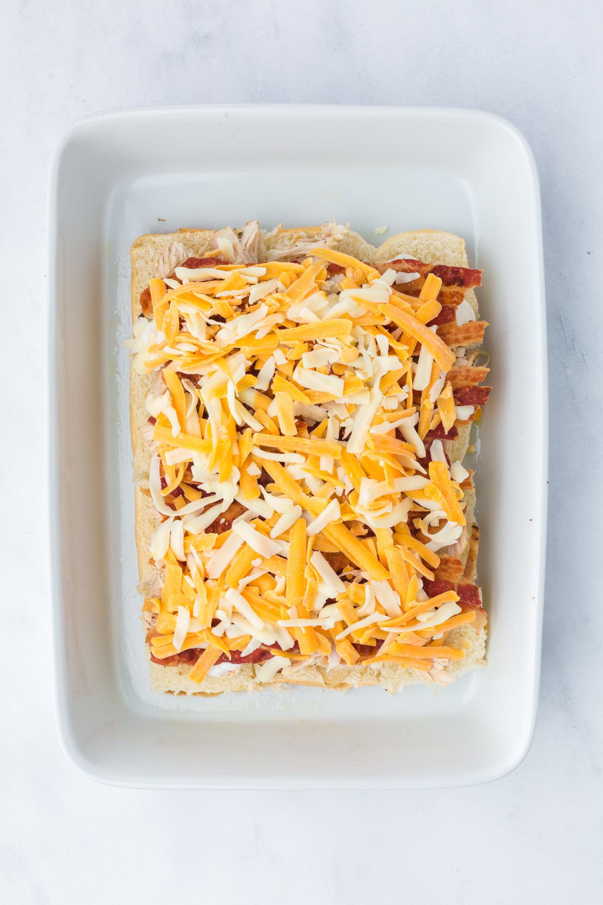 A sprinkling of shredded cheese is added on top of bacon.