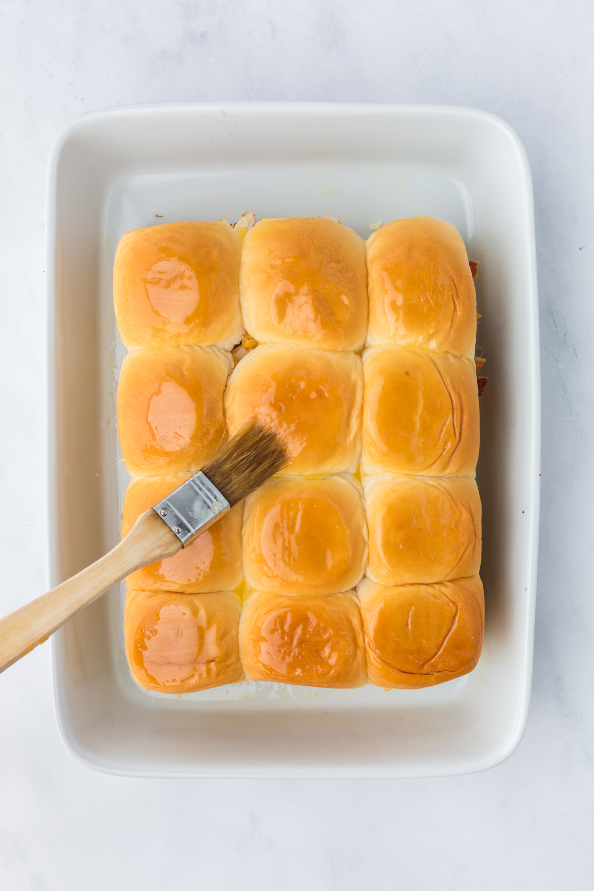 Top buns are added and butter is brushed all over.