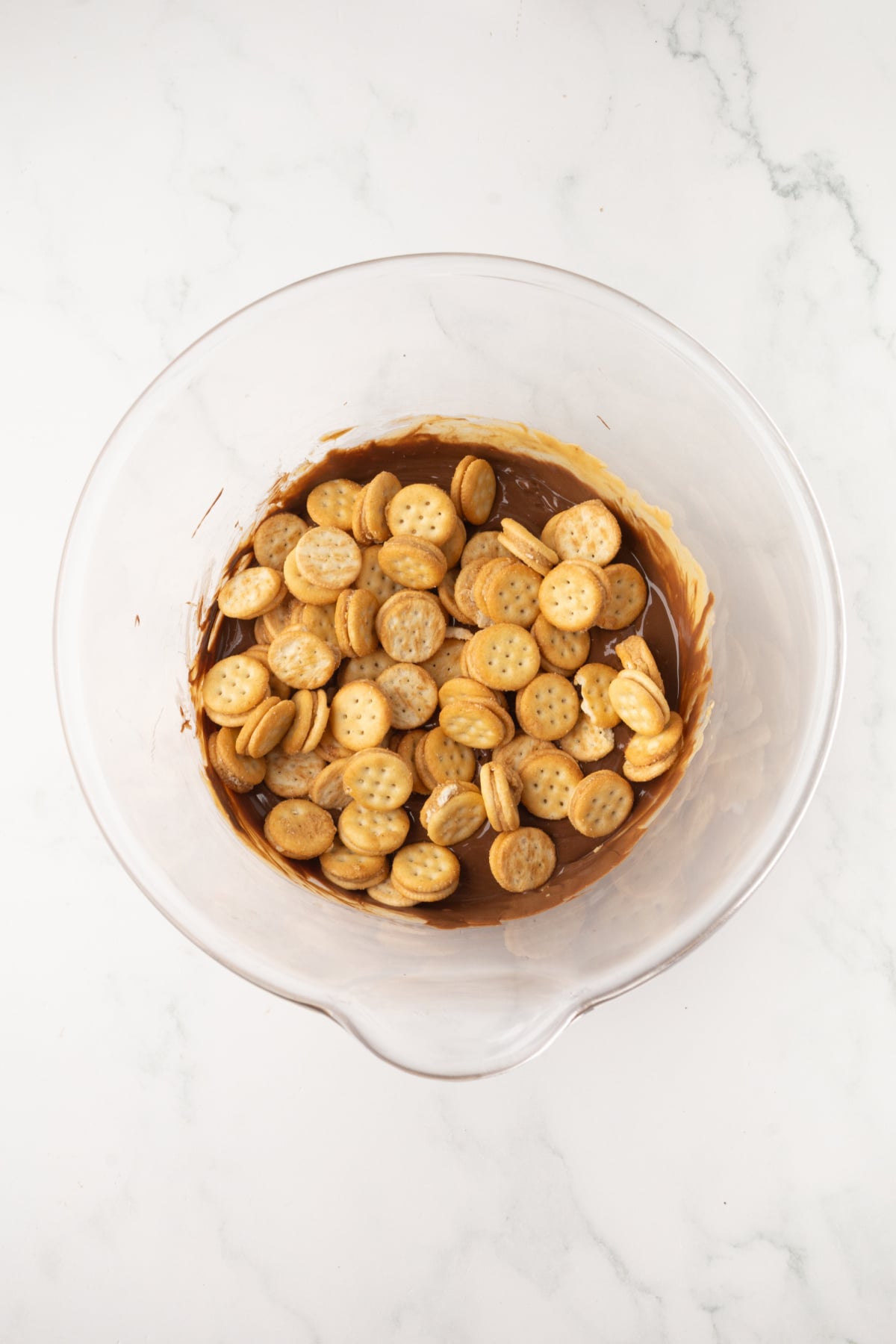 mixing ritz crackers with melted chocolate mixture in a bowl