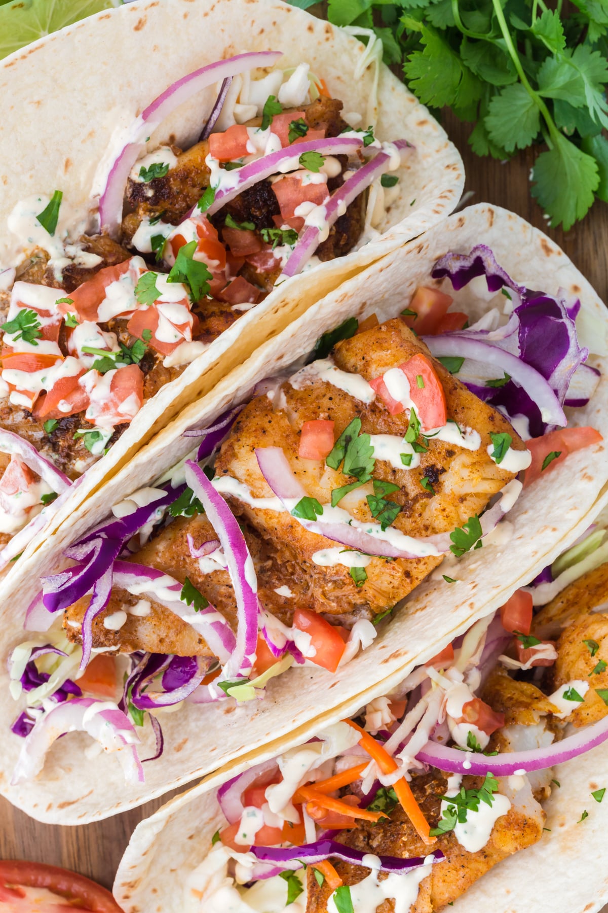 Blackened fish tacos topped with tomatoes, onions, and sauce in a dish.