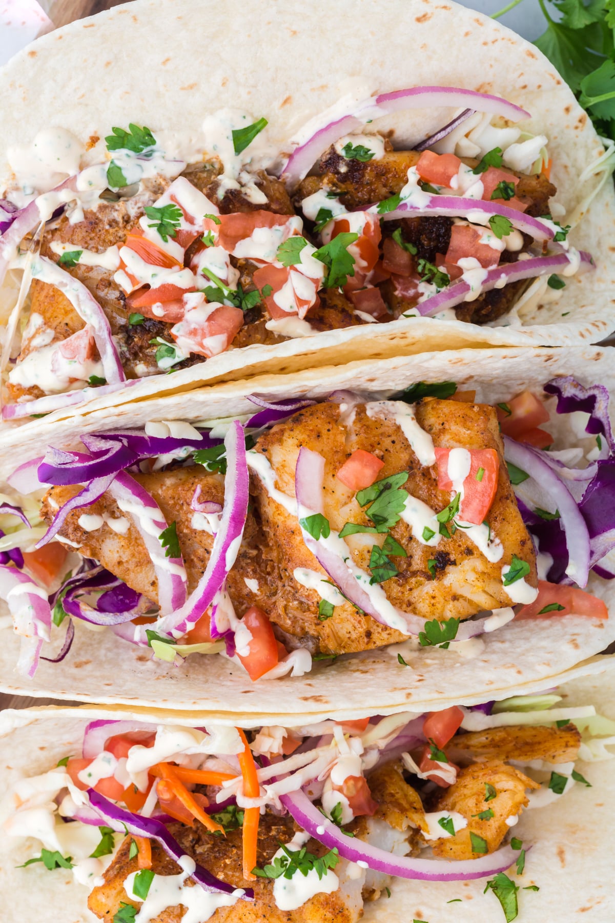 Three fish tacos next to one another.