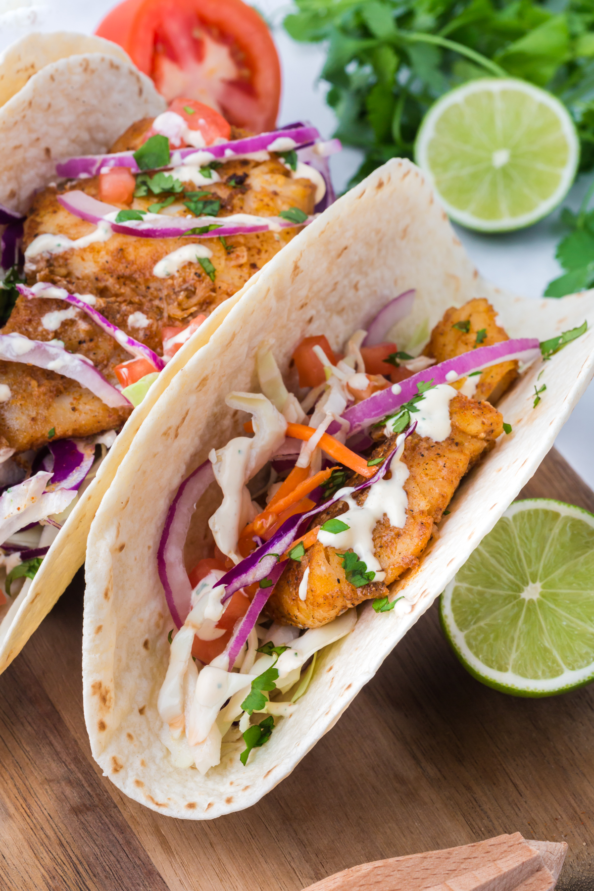 A fish taco with coleslaw, onions, and sauce on top.