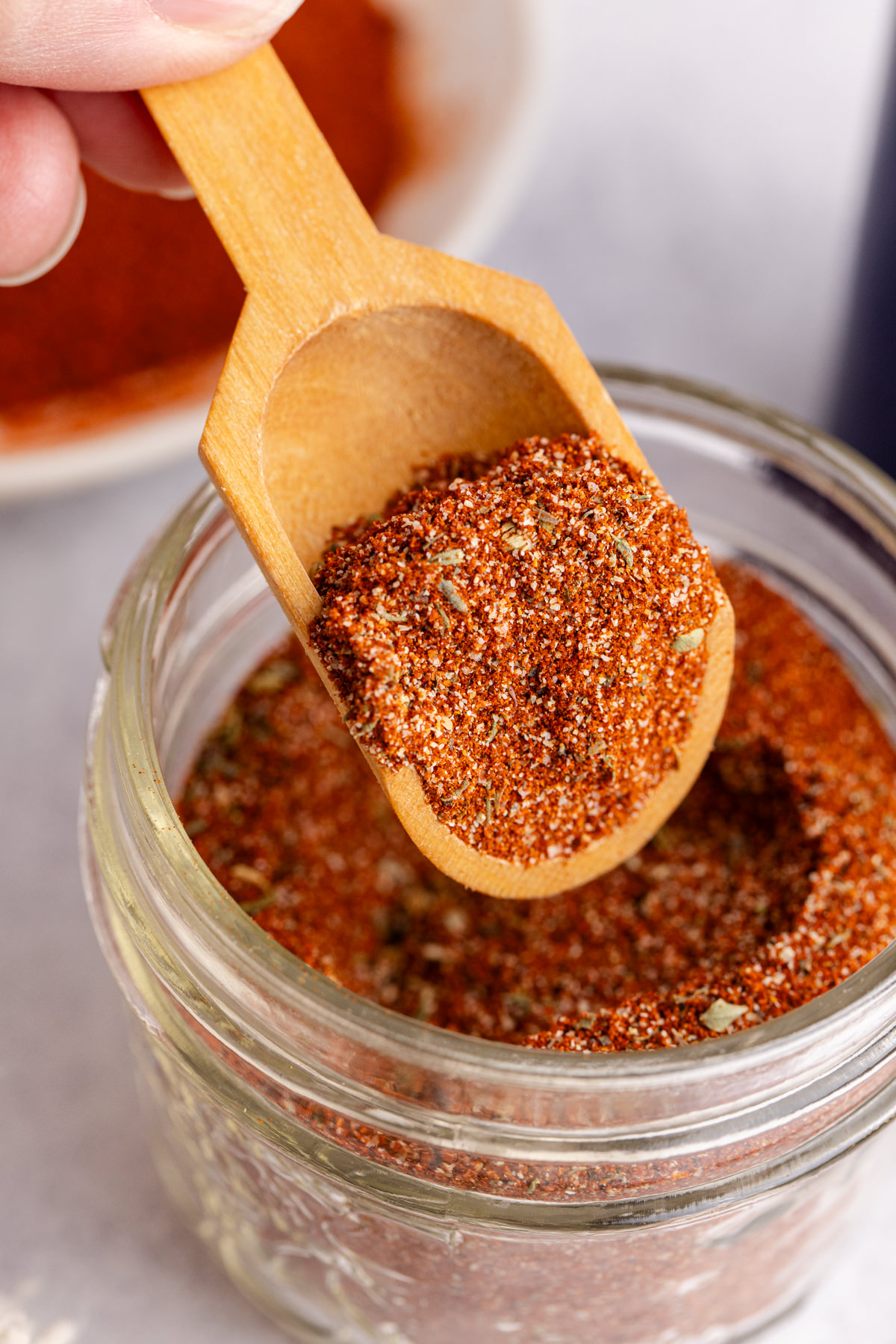 Blackening seasoning being scooped out of a glass jar.