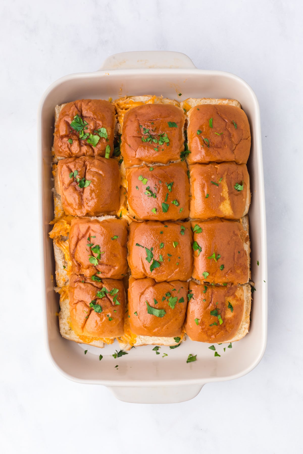 Baked sliders in pan with a sprinkling of chopped parsley