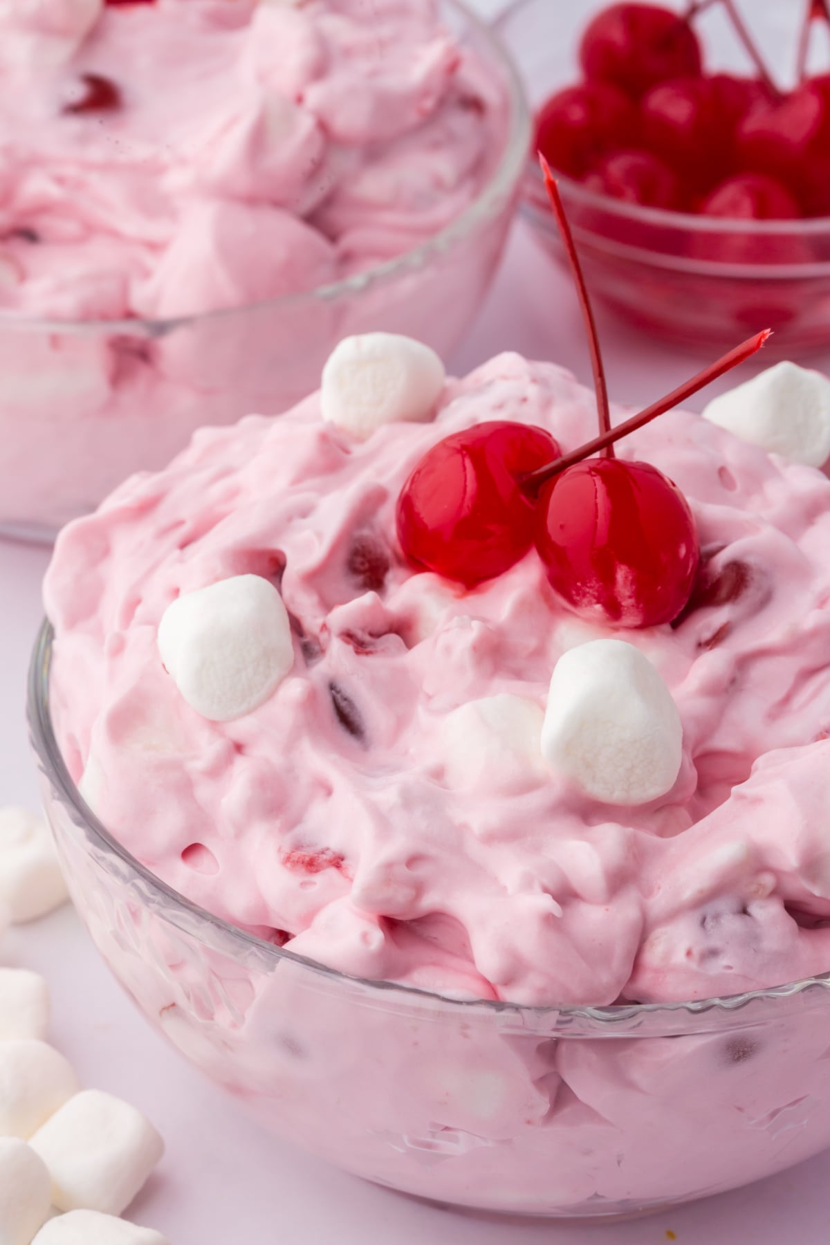 Cherry fluff salad marshmallow and cherries on top on a table.
