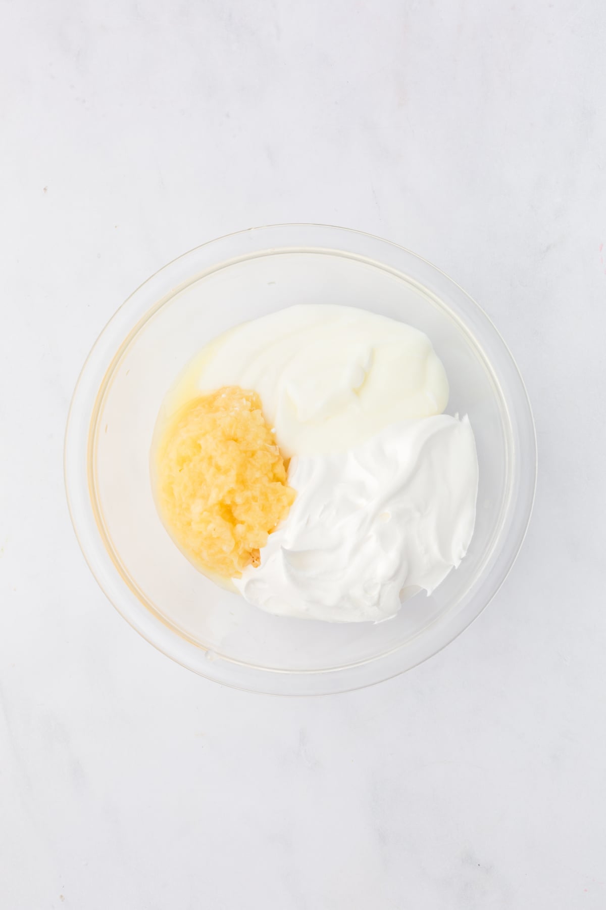 Yogurt, whipped topping and crushed pineapple in a bowl.