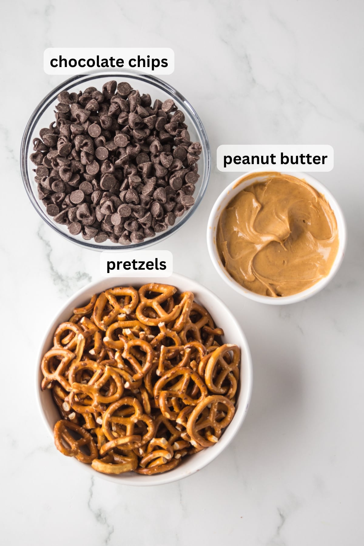 ingredients for chocolate peanut butter pretzels including pretzels peanut butter and chocolate chips in bowls on table