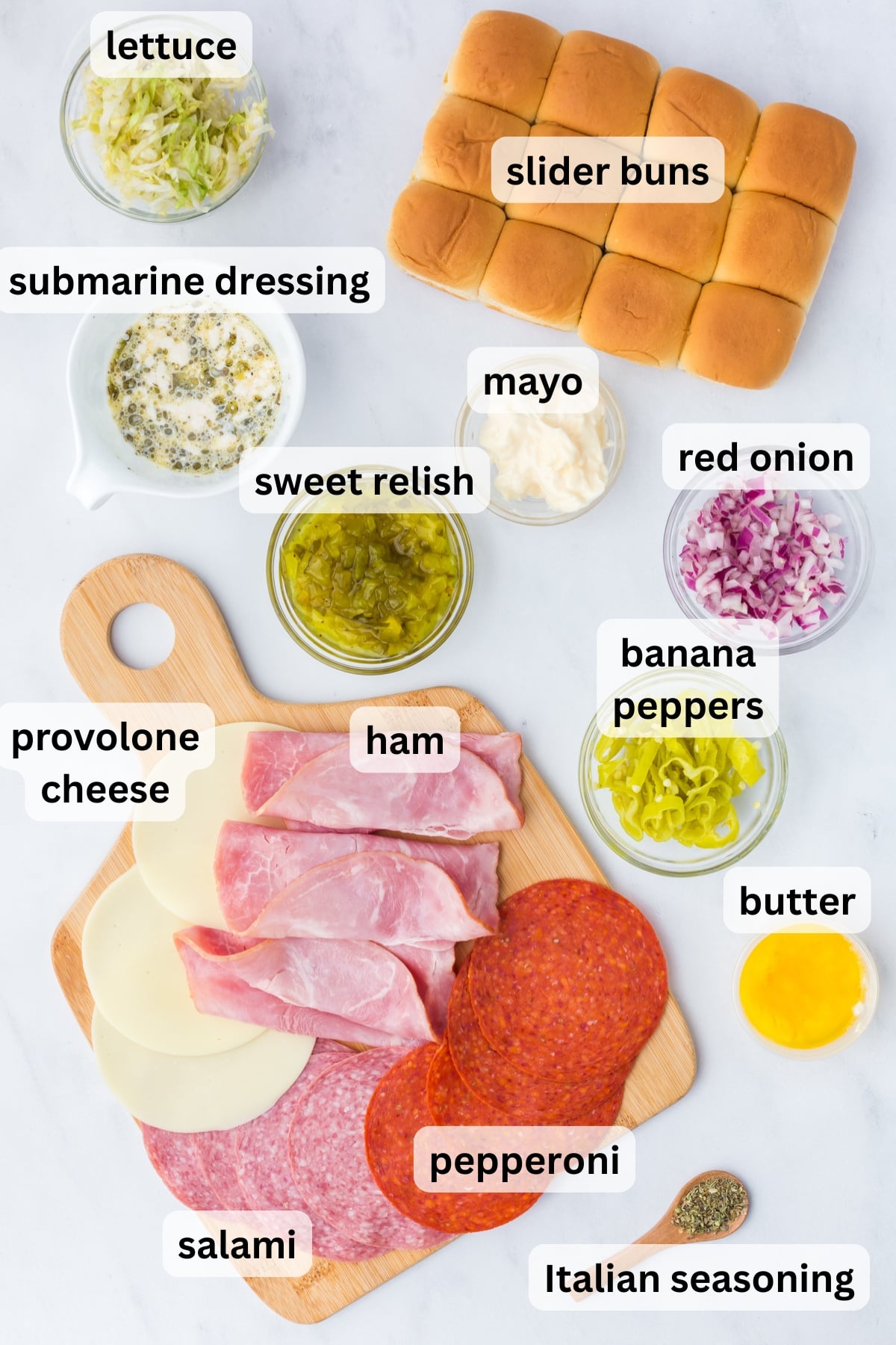 All of the ingredients needed to make Chopped Italian Sliders in bowls and on cutting board on table