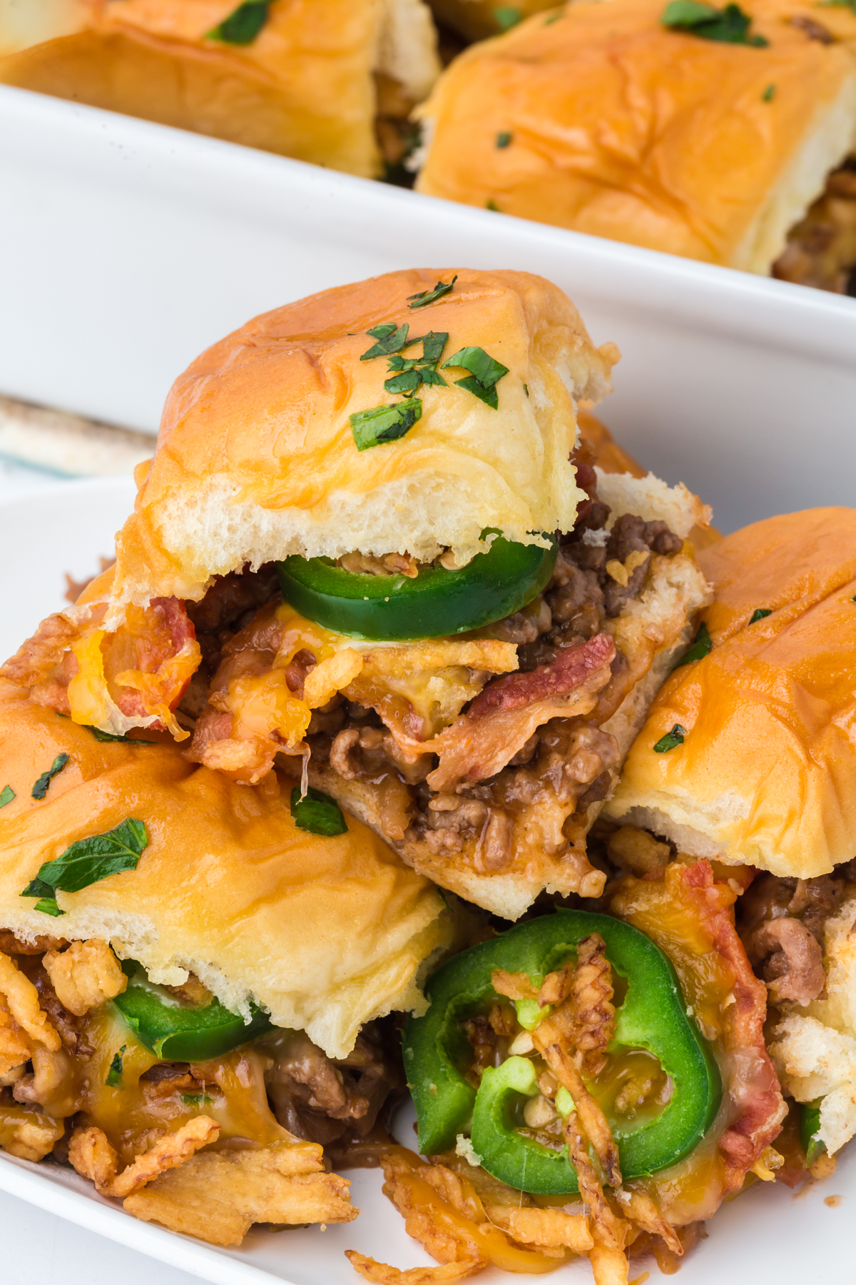 A few sliders in baking dish with one on top.