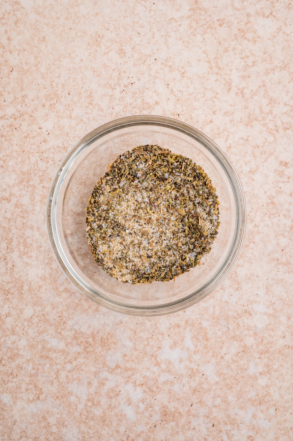 a small bowl filled with kosher salt, garlic powder, onion powder, dried oregano, dried basil and coarse ground pepper.
