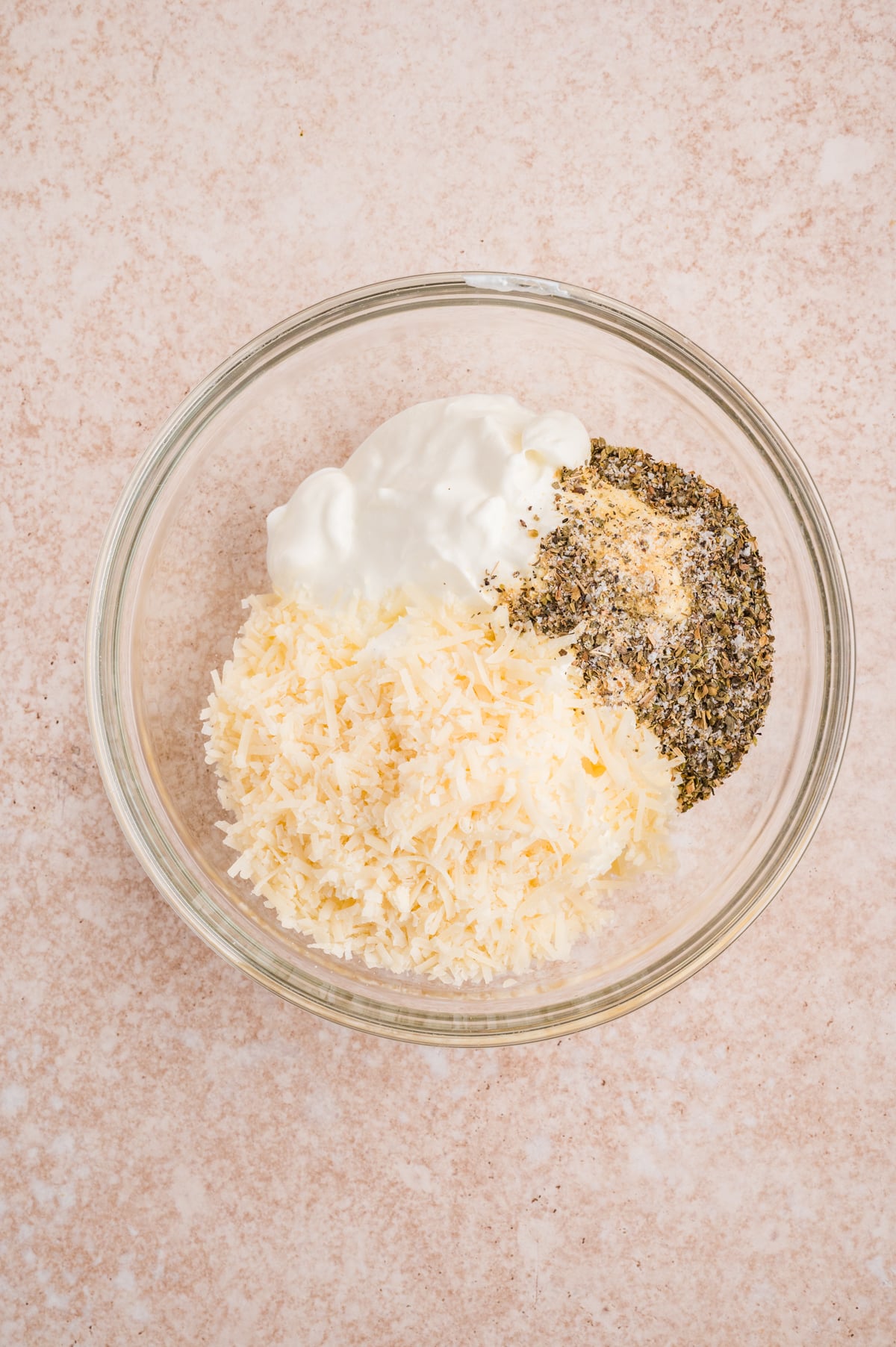 a mixing bowl filled with sour cream, parmesan cheese and other half of seasoning mixture 