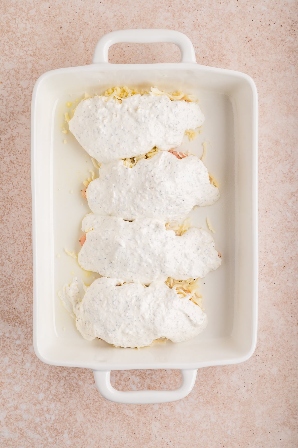 sour cream mixture spread on top of chicken in baking dish