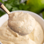 A spoon holding up some fish taco sauce.