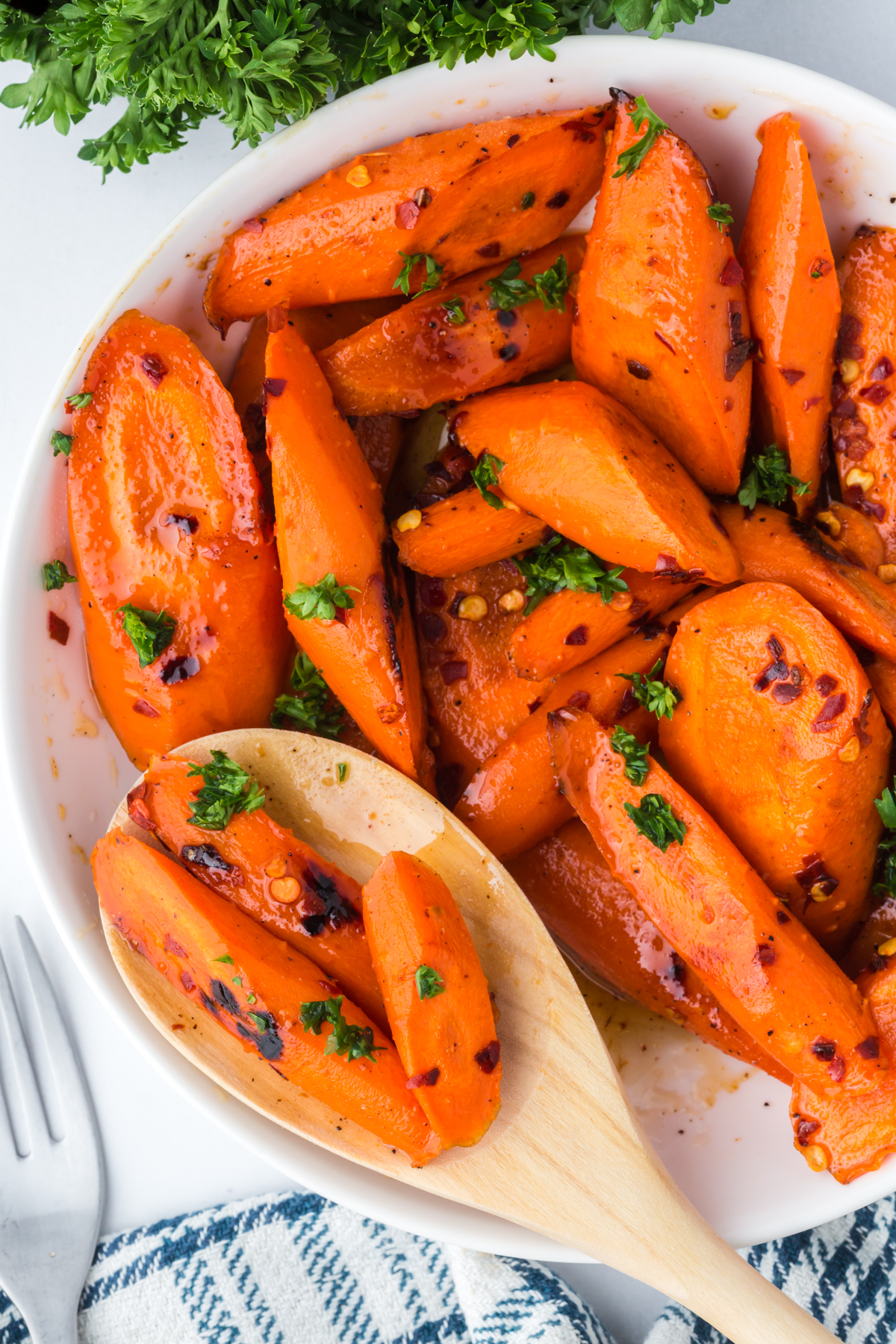 A wooden spoonful of carrots leaning on a bowlful