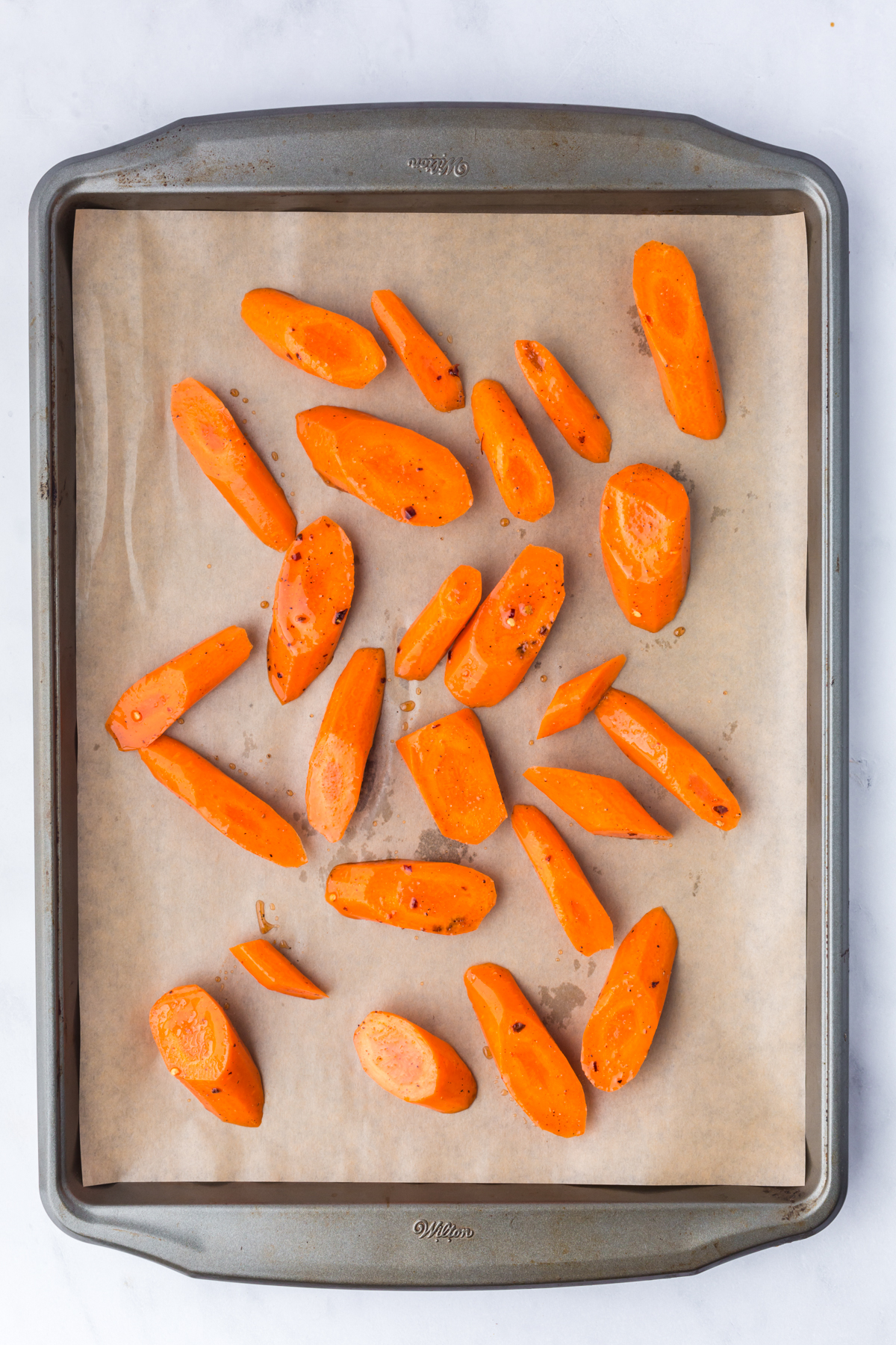 Carrots spread out on parchment covered baking sheet