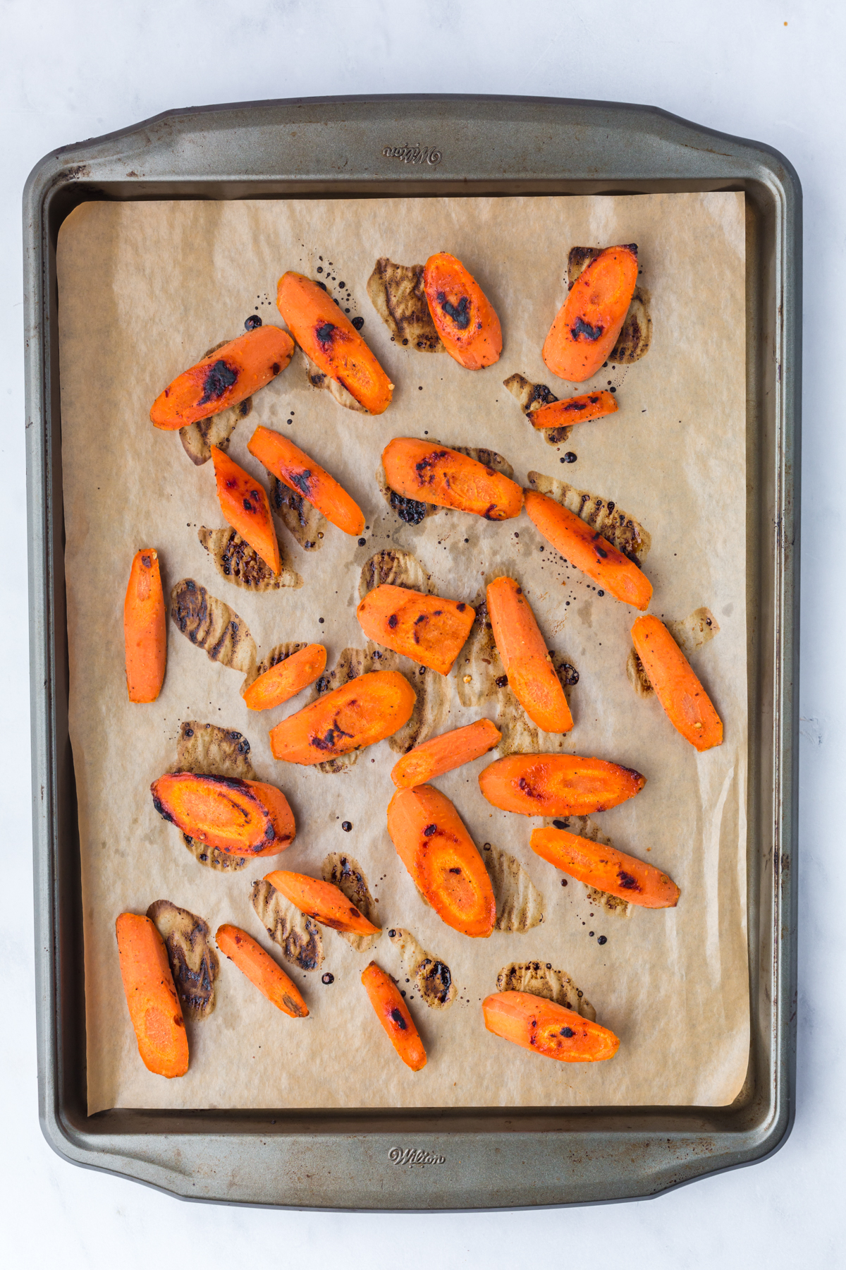 Roasted hot honey carrots caramelizing on a baking sheet.