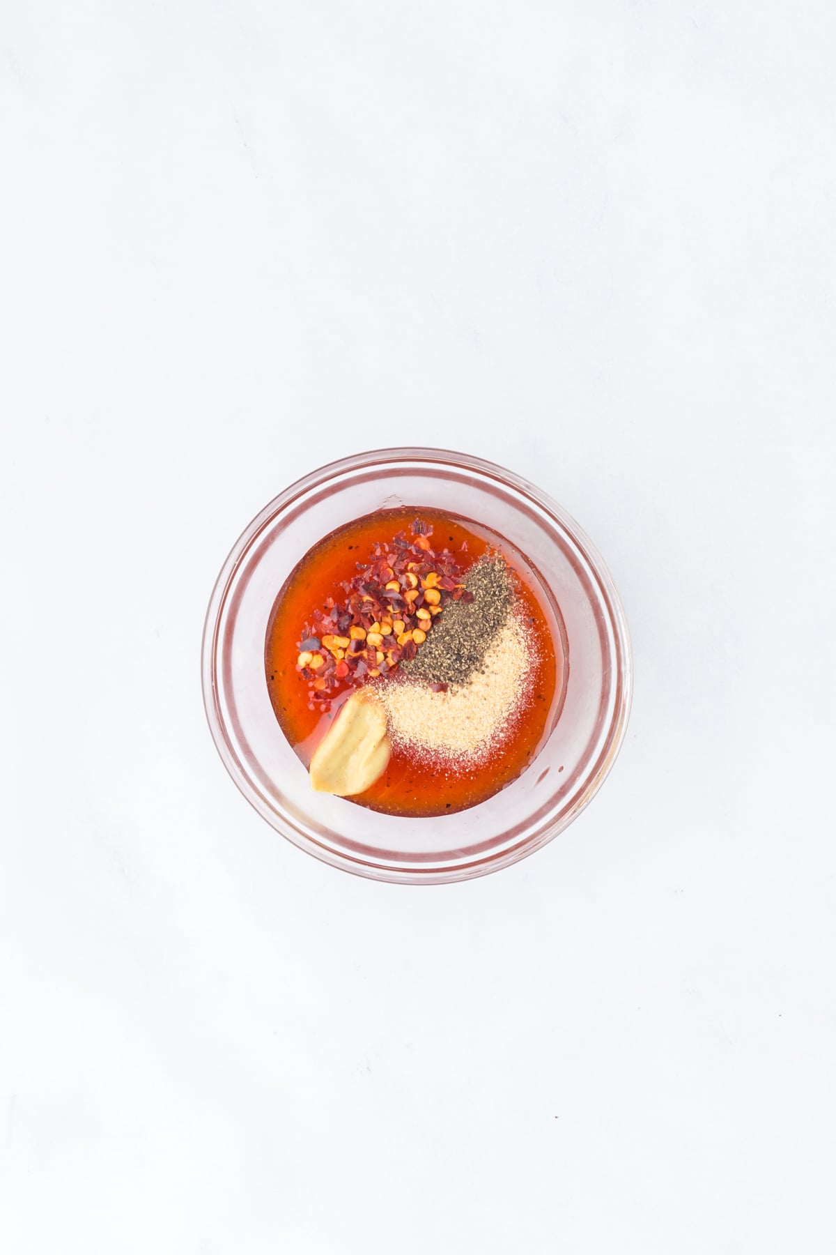 hot honey, Dijon, garlic powder, pepper, and red pepper flakes in bowl