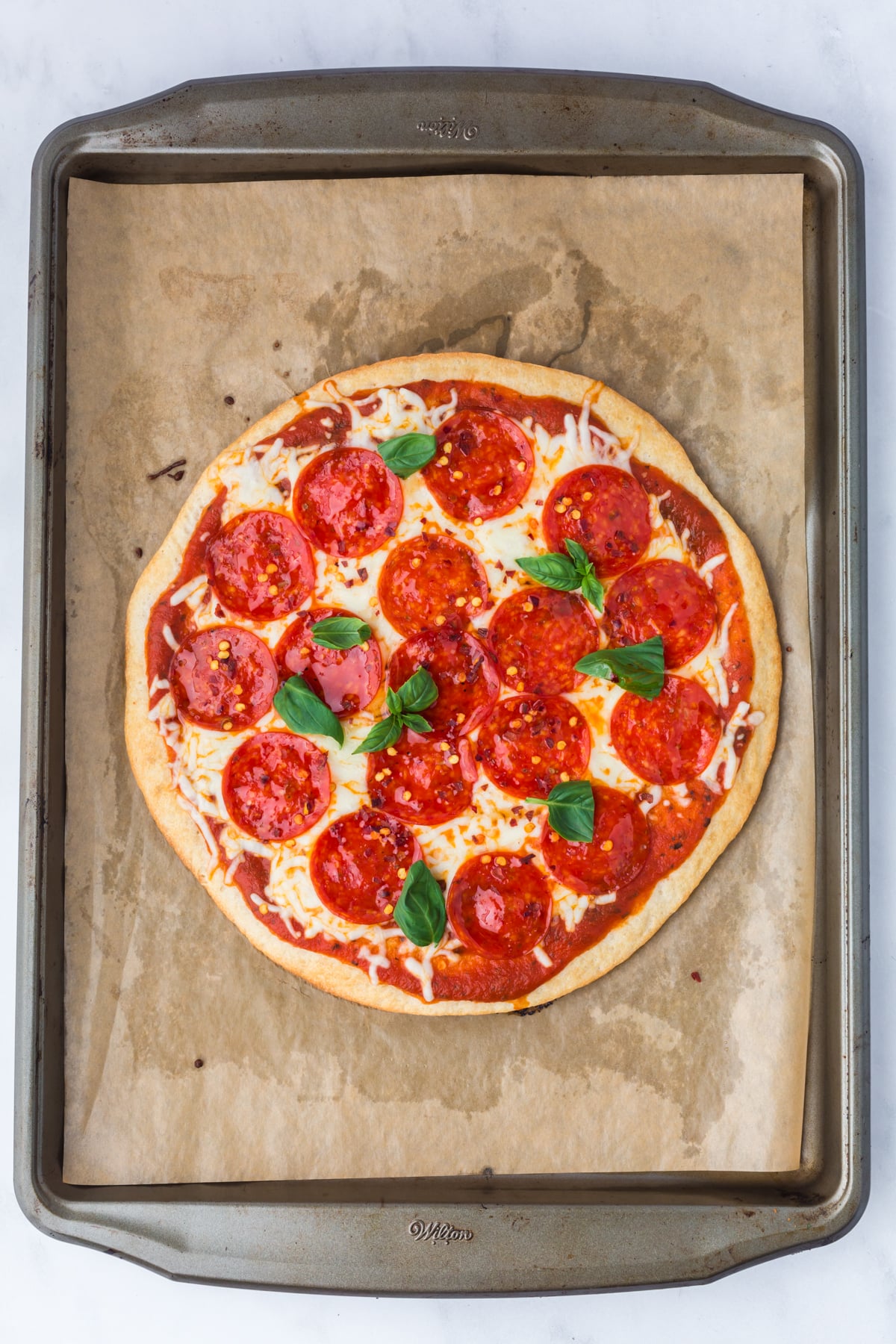 A baked pizza on a parchment covered baking sheet.