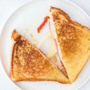 An Italian grilled cheese on plate cut in half with melted cheese in between each half.
