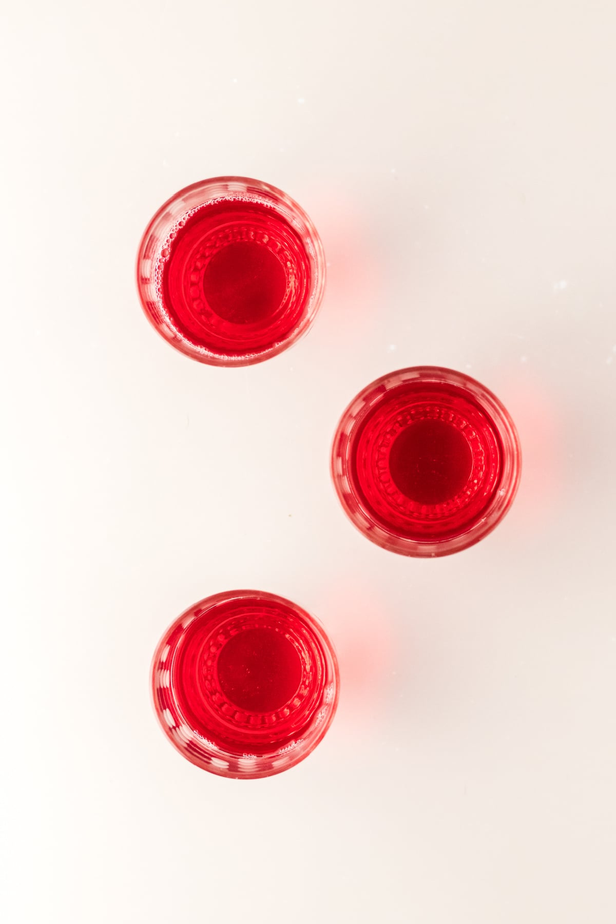 Three glasses on a table with the first or bottom layer of Jello added.