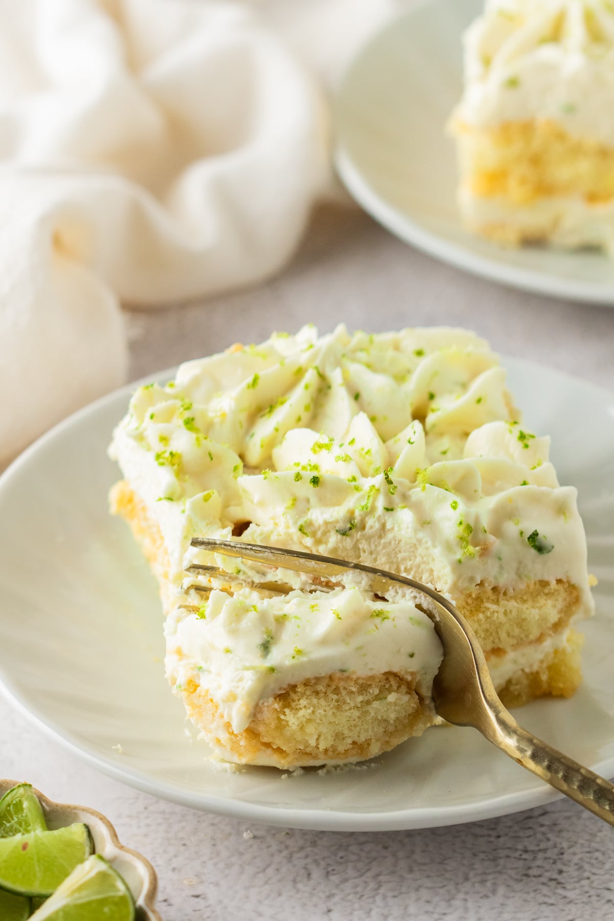 A slice of key lime tiramisu being eaten with a fork.