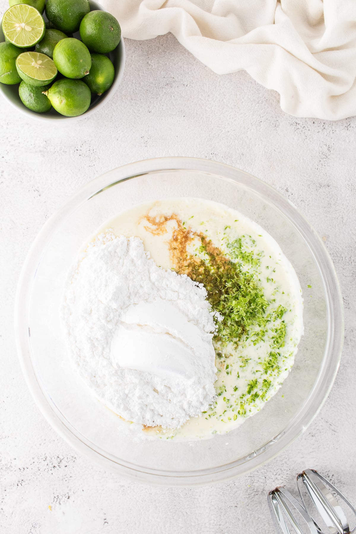 Mascarpone, cream, powdered sugar, vanilla, lime juice and zest in a bowl.