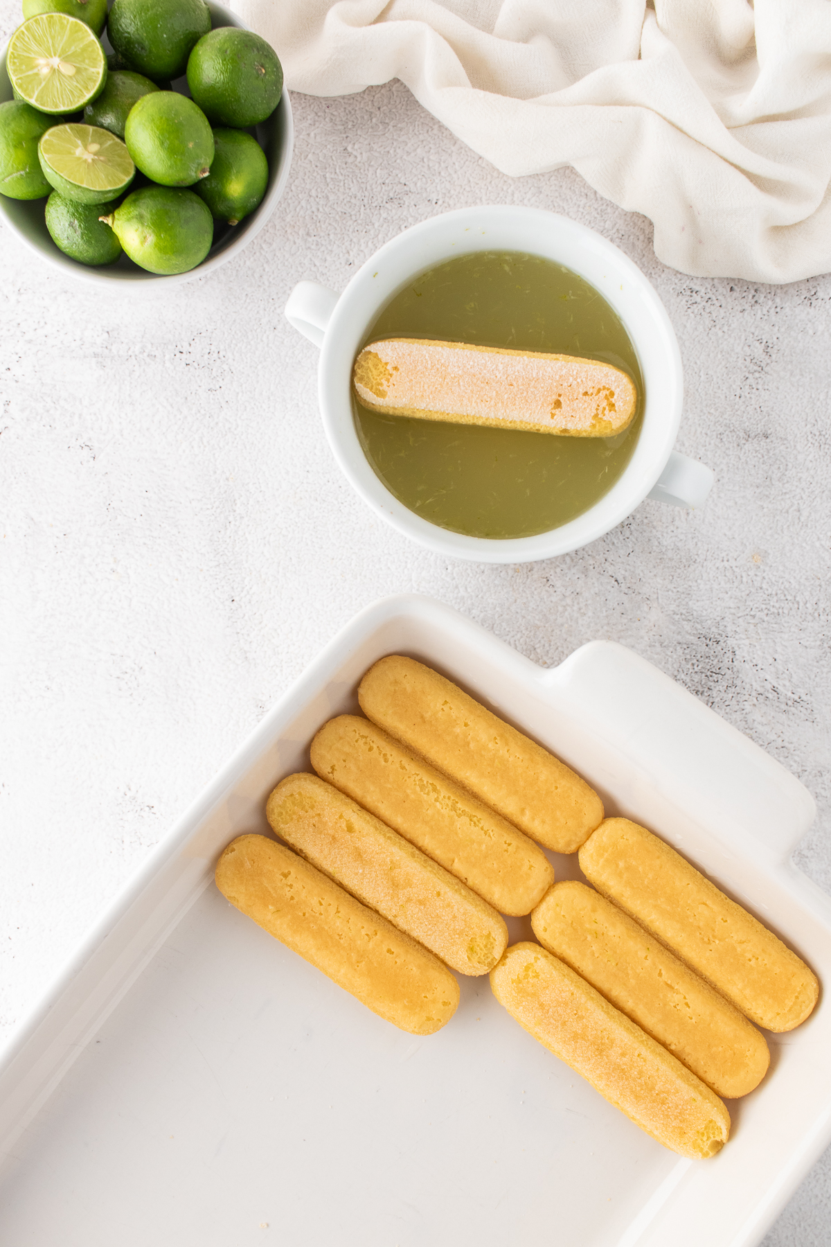 The ladyfingers dipped into the lime juice and placed in a casserole dish.