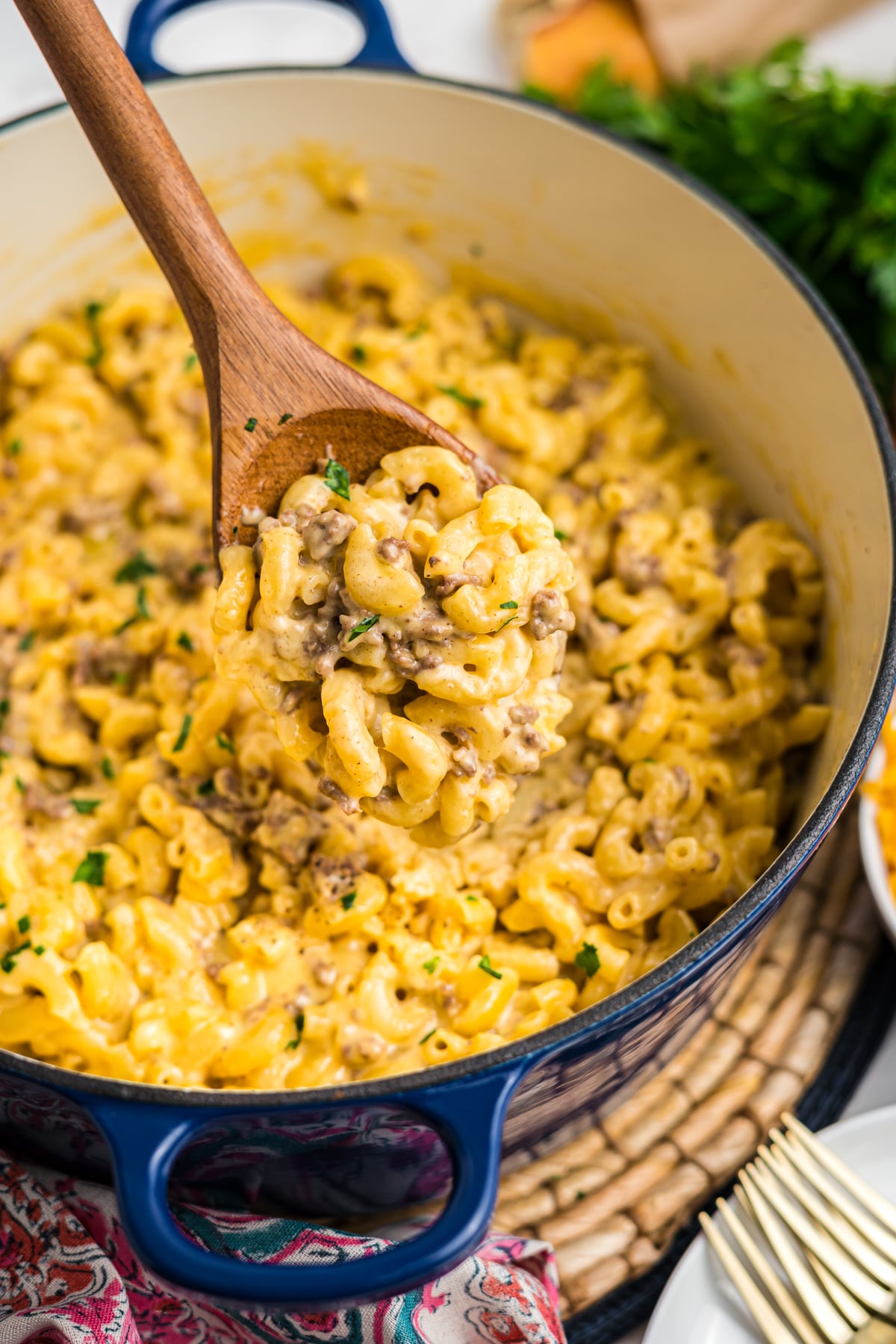 A wooden spoon picking up some mac and cheese with ground beef.