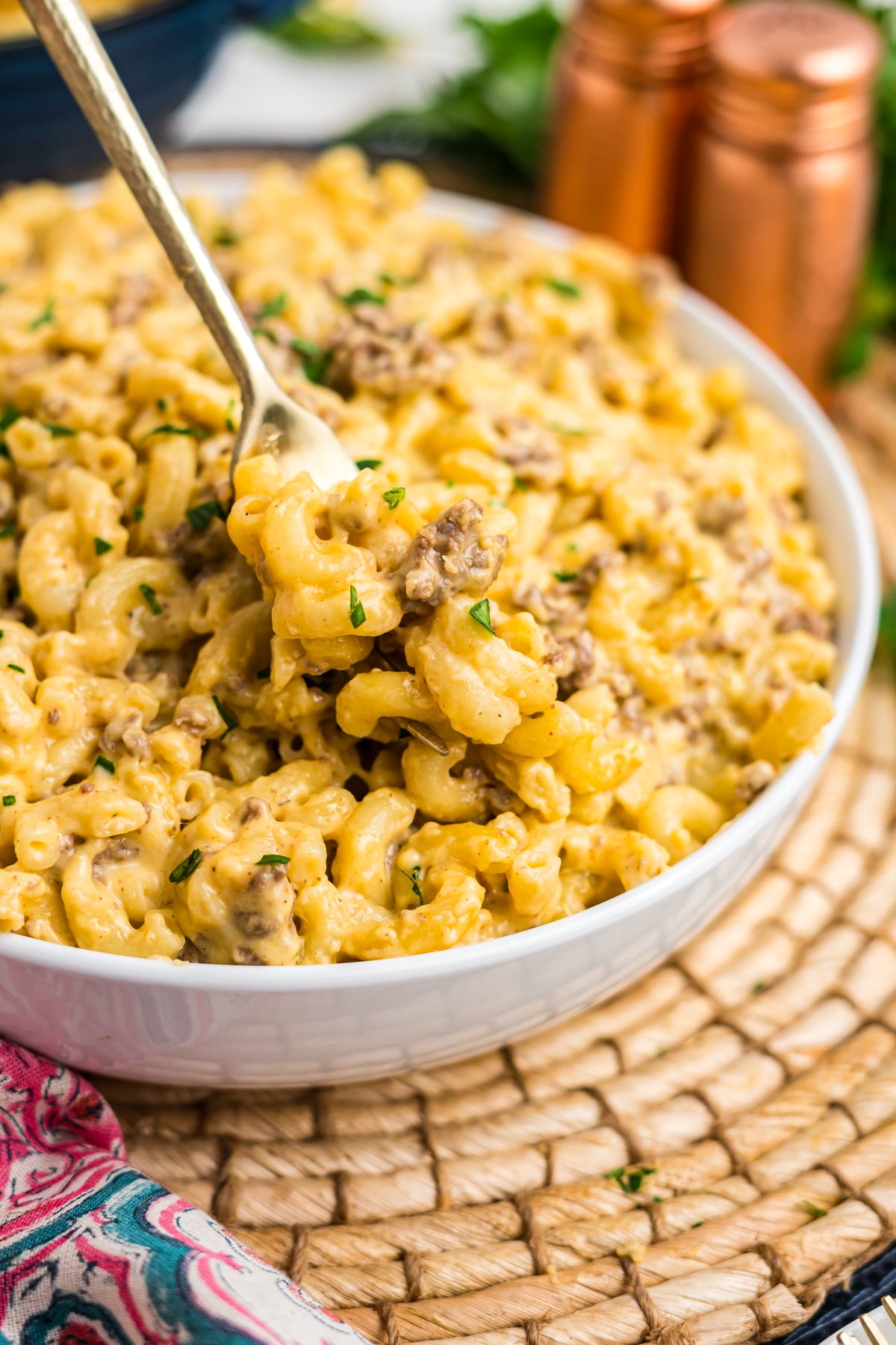 A bowl of beef macaroni and cheese with a spoon lifting up a bite. 