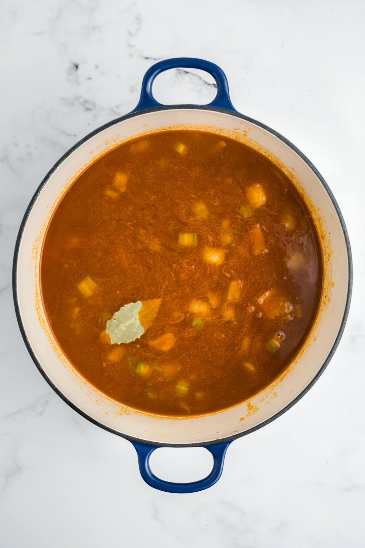 Broth and other ingredients added to the pot to make meatball stew. 
