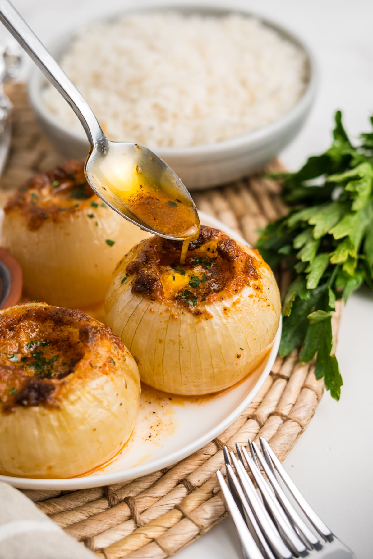 Onions on plate with a spoon drizzling butter mixture on top