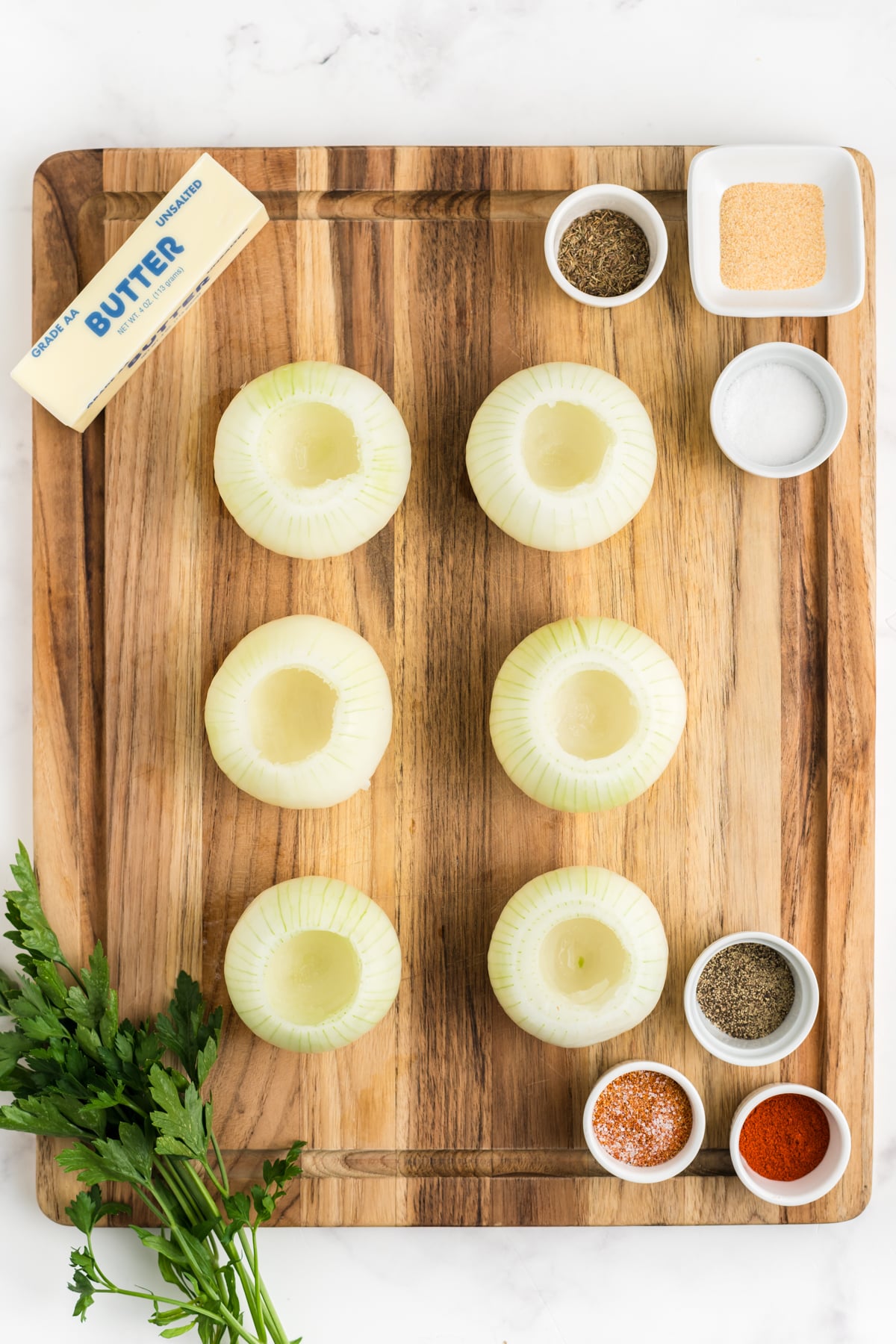 Six onions on a cutting board with paret of the core removed.