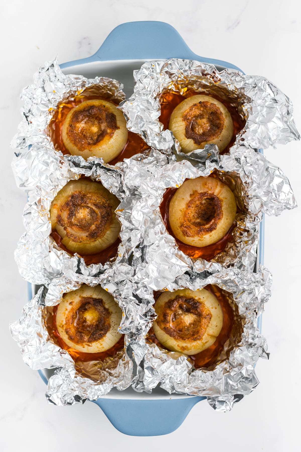 Six baked onions with foil opened at top