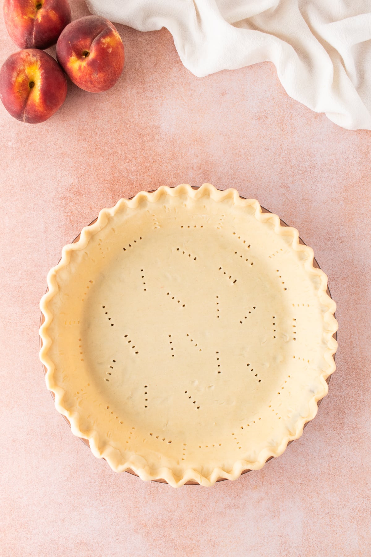 The pie crust rolled out to fit the 9-inch pie pan with edge trimmed and fluted ready to be chilled