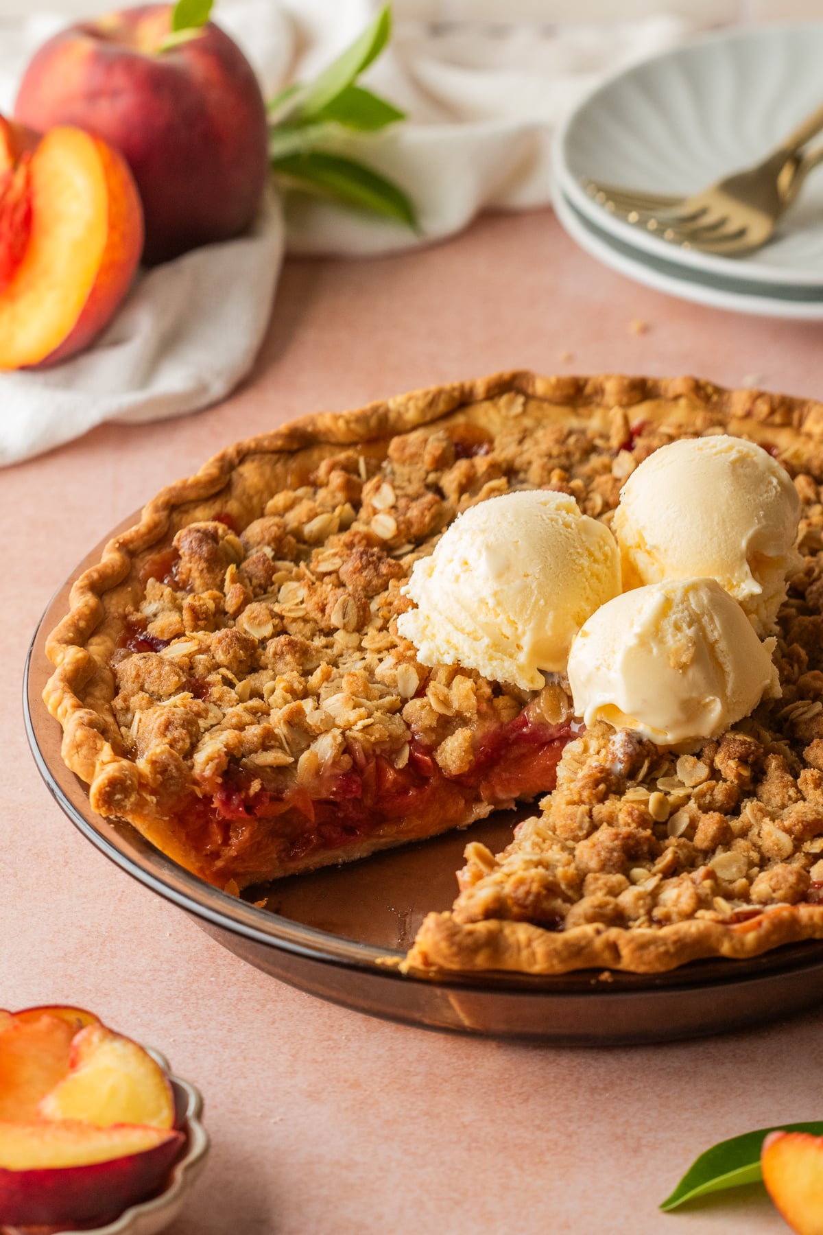 A pie on a table missing a slice and 3 scoops of ice cream on top
