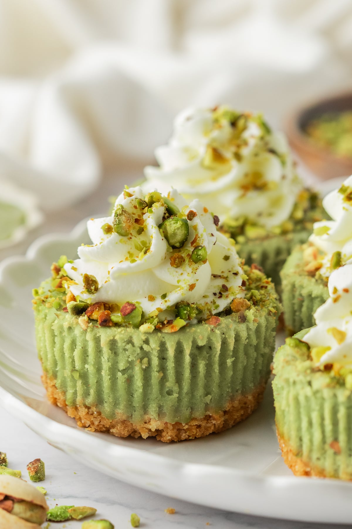 Cheesecakes with whipped cream and pistachios on top.
