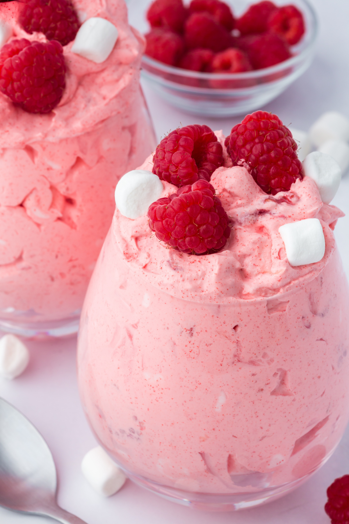 raspberry fluff salad in bowls on table garnished with raspberries and marshmallows