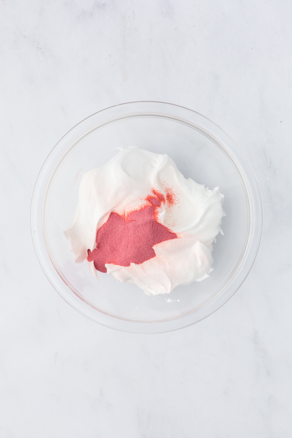 A large bowl with raspberry Jell-O powder and whipped topping.