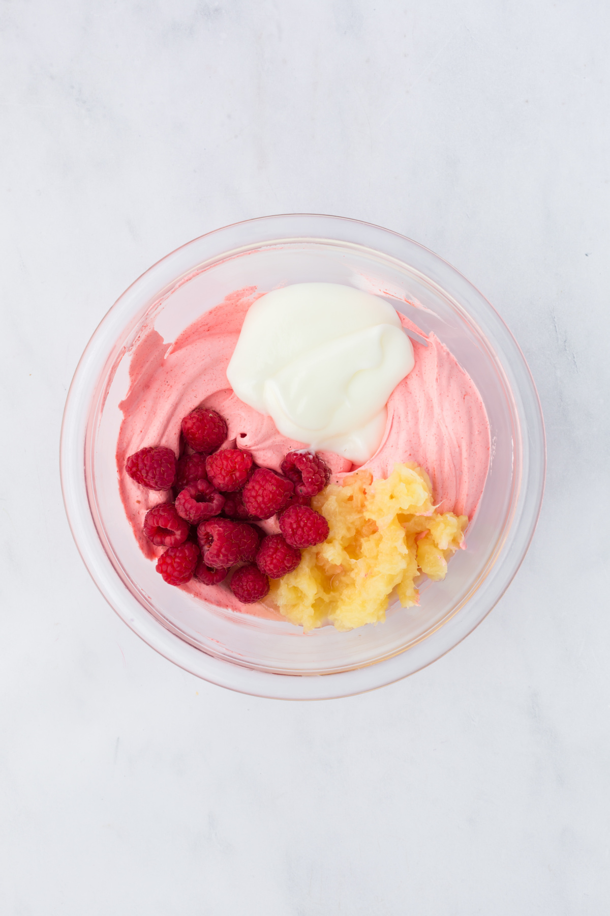 The raspberries, crushed pineapple, and vanilla yogurt are added to whipped topping mixture.
