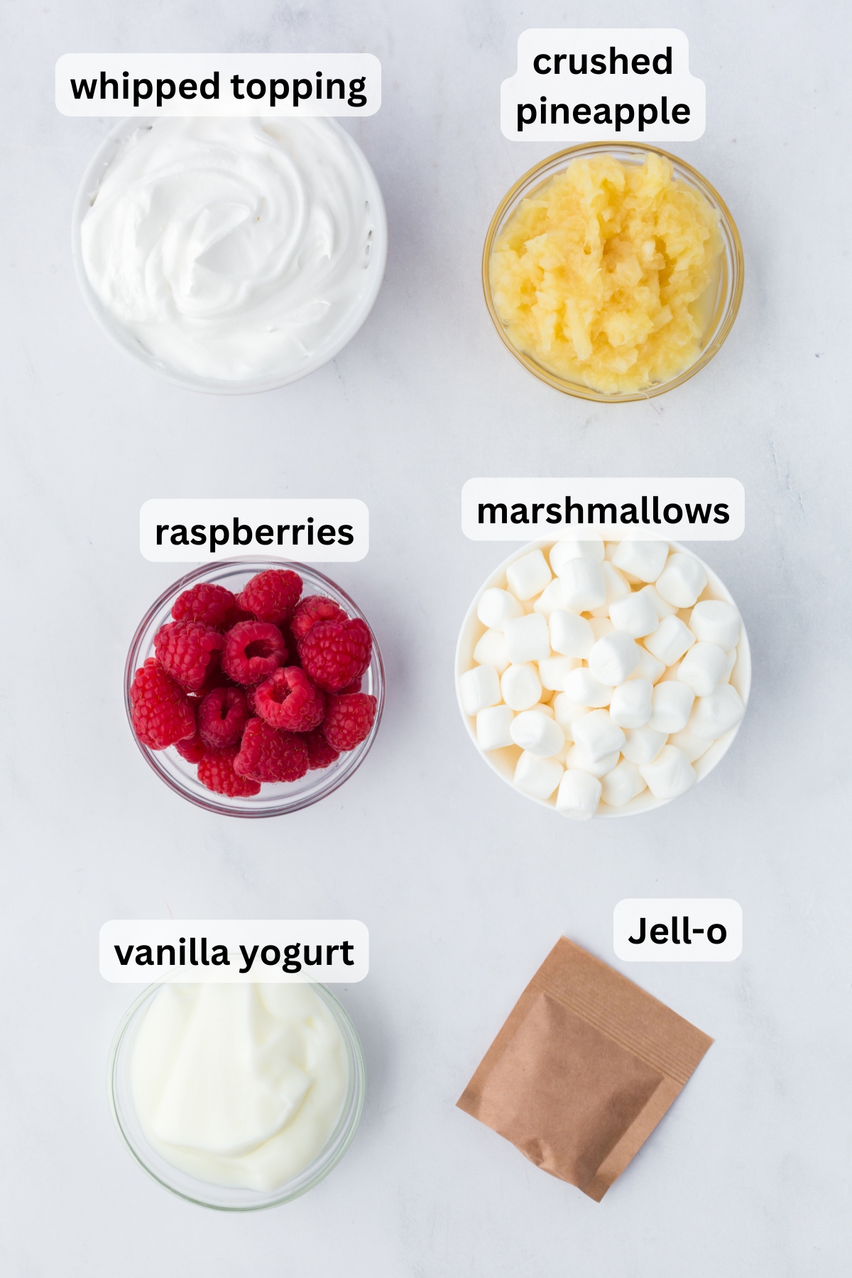 All of the ingredients needed to make raspberry fluff in bowls on a table.