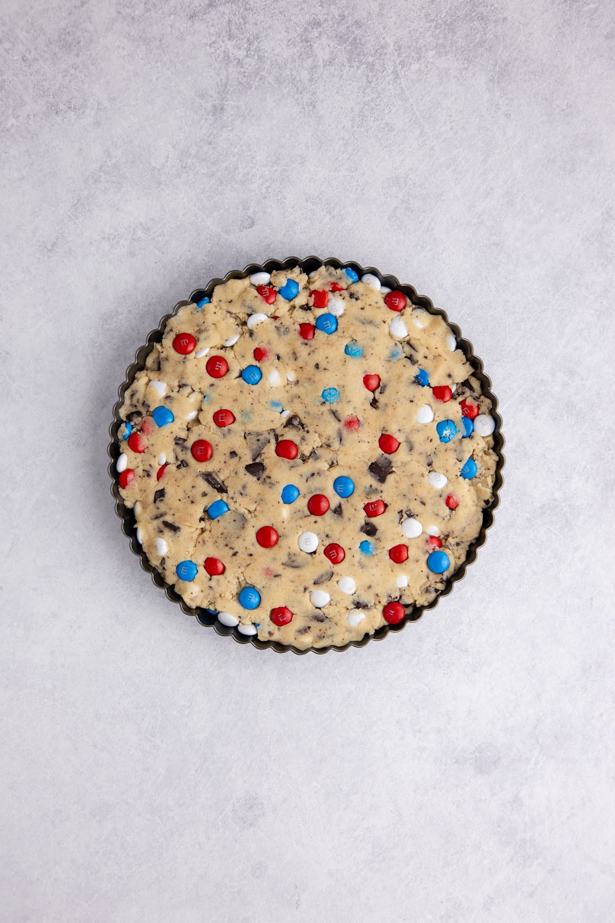 Cookie dough pressed into tart pan with m&ms