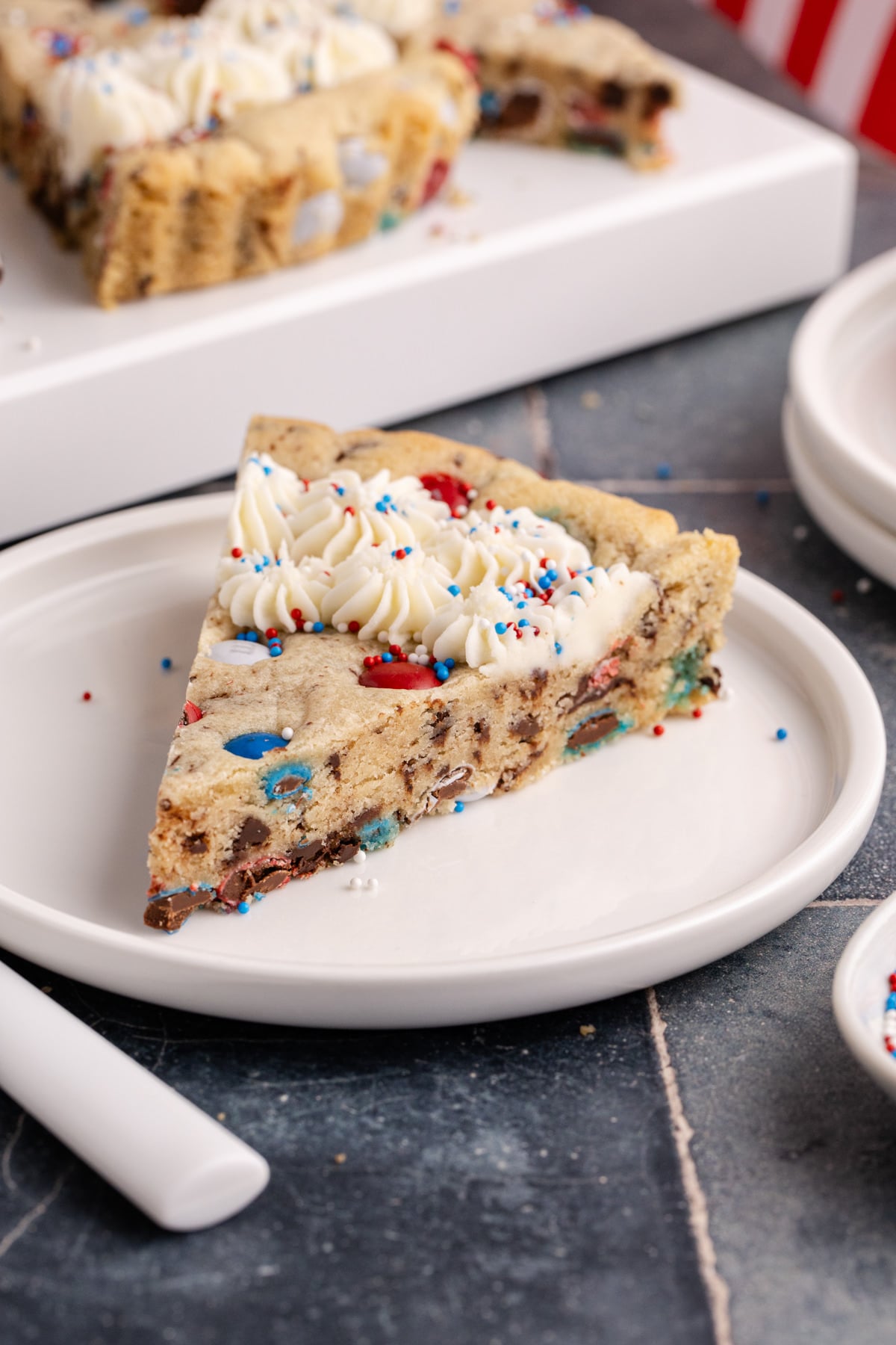 A slice of cookie cake on a white plate