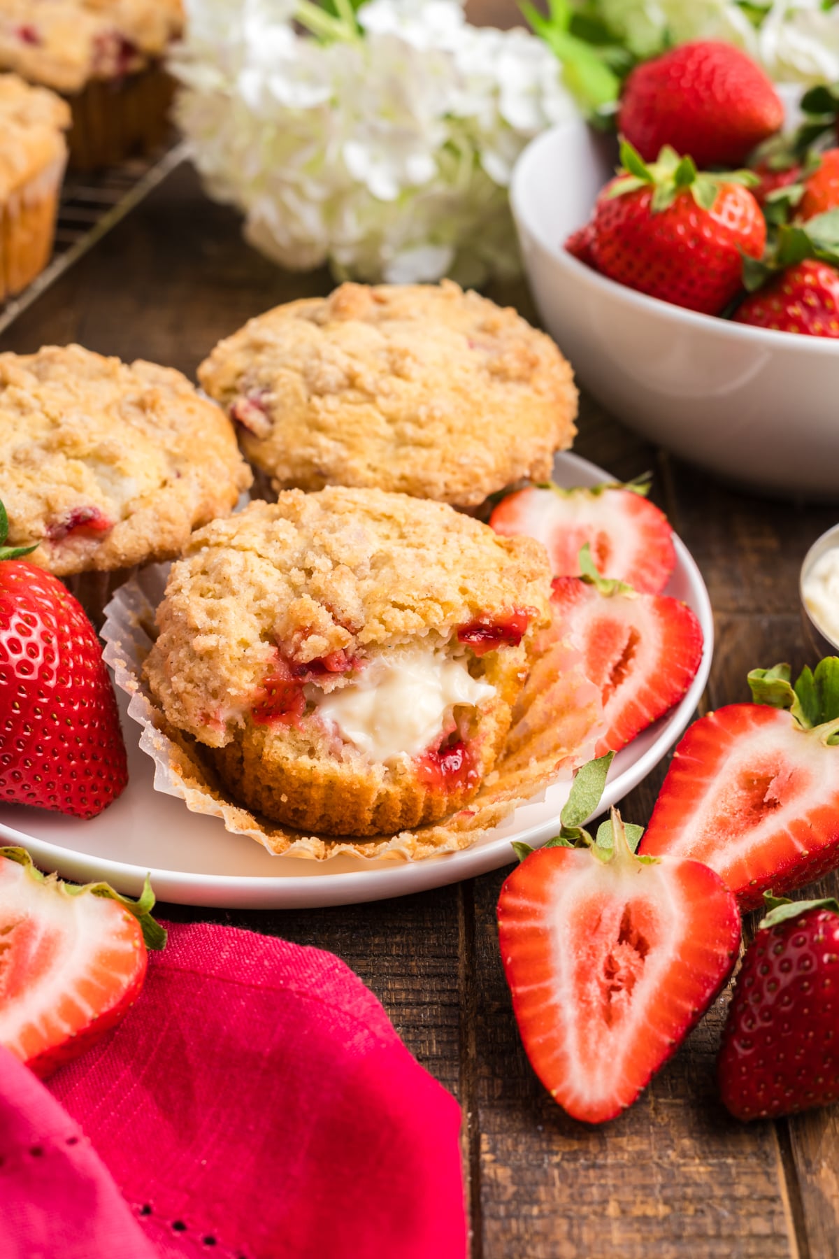 A strawberry muffin with cheesecake filling on a plate.